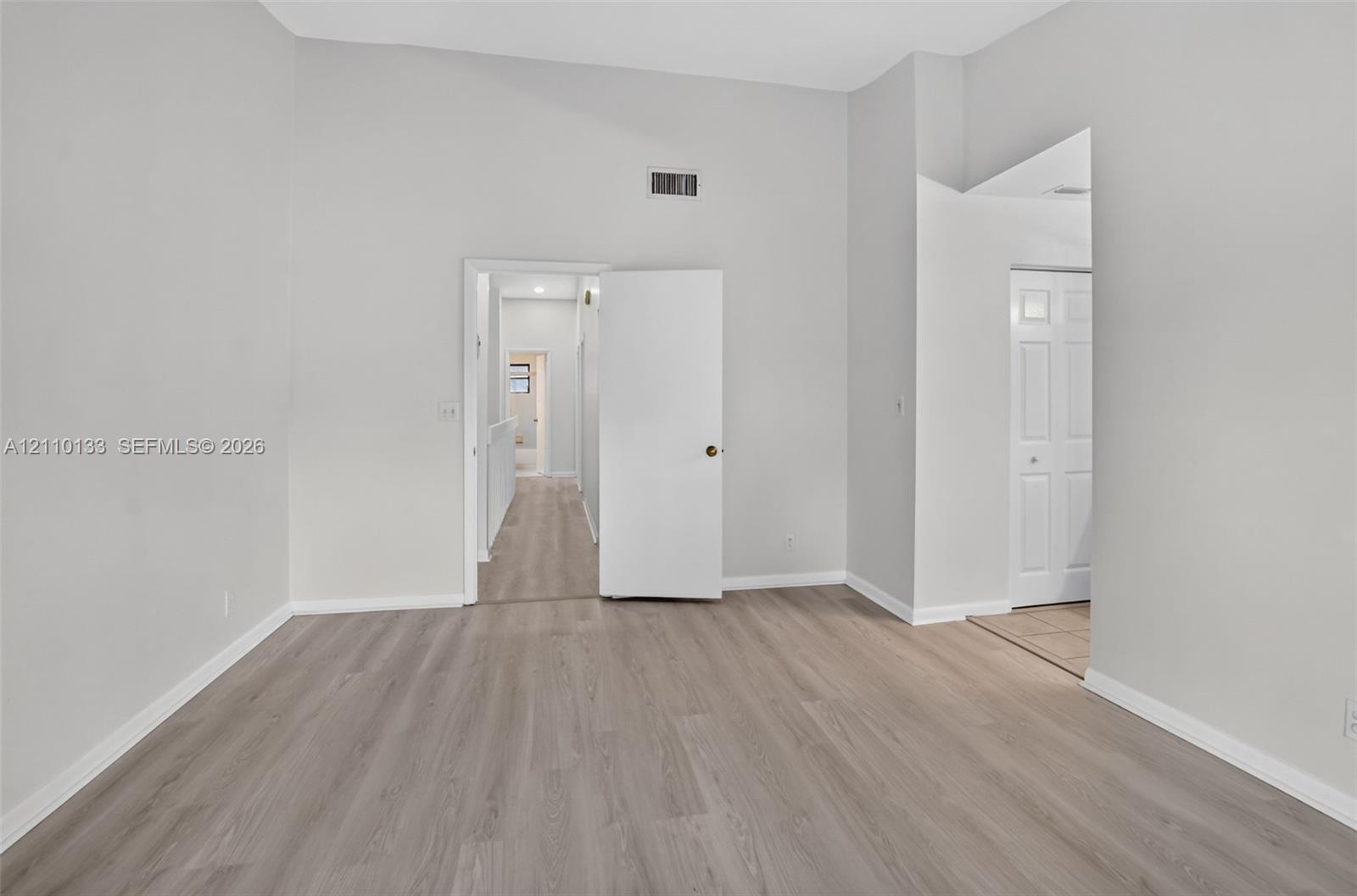 Interior room featuring vaulted ceilings, wood-finish flooring, and crisp neutral wall paint