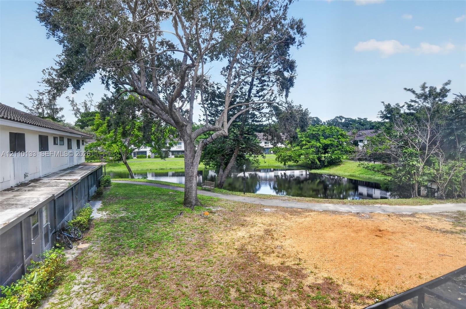 Exterior grounds featuring a paved pathway, mature trees, and a water feature