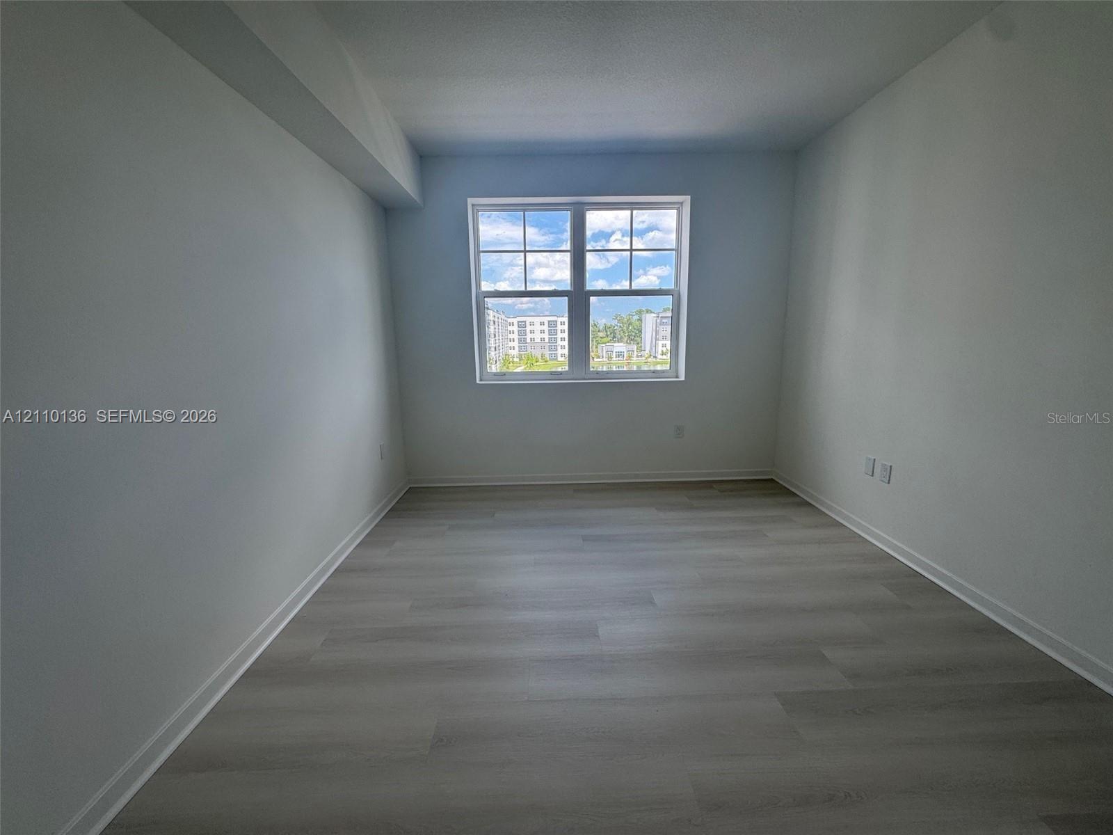 Neutral-toned interior space featuring wood-finish flooring and a multi-pane window