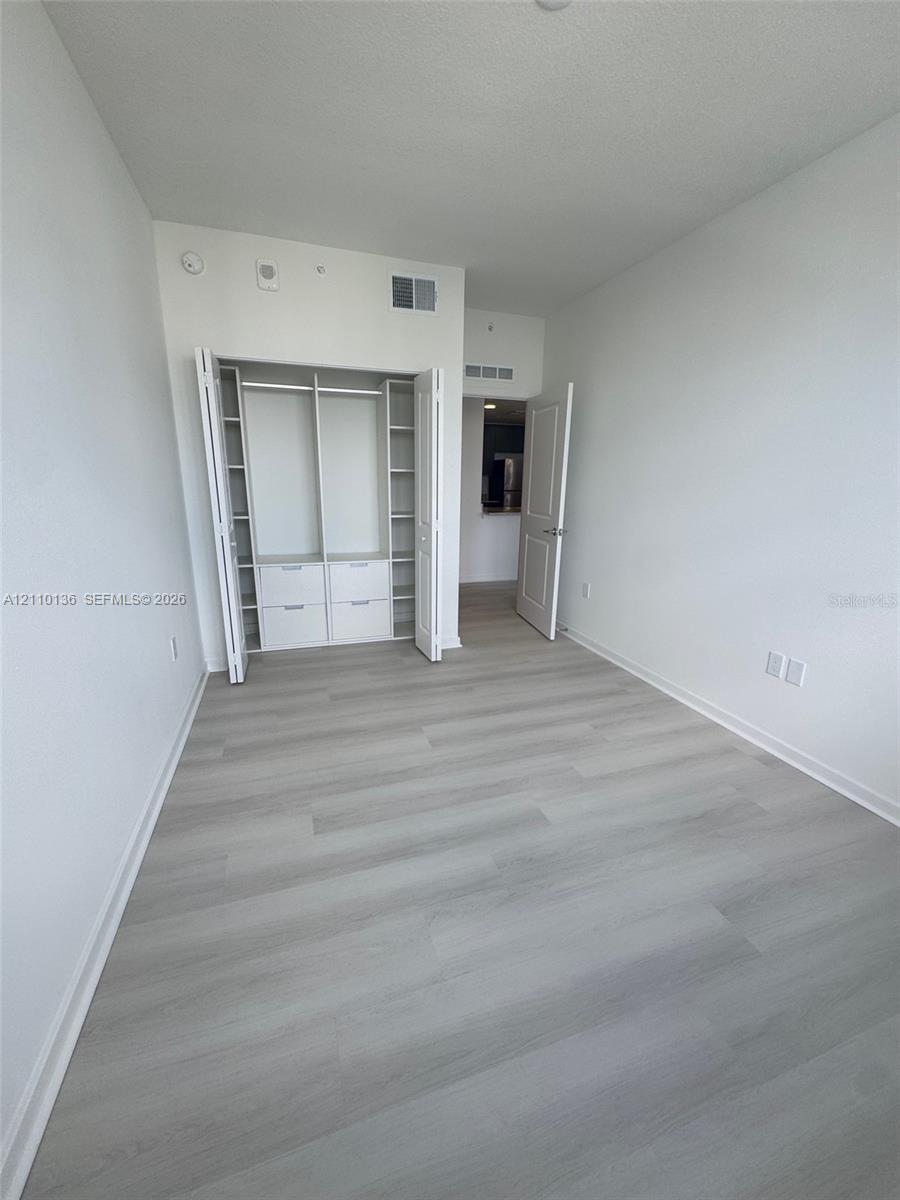 Interior space featuring wood-finish flooring and a built-in closet system with integrated shelving and drawer storage