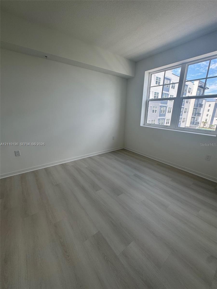 Interior room featuring light-toned wood-finish flooring, neutral walls, and a large multi-pane window