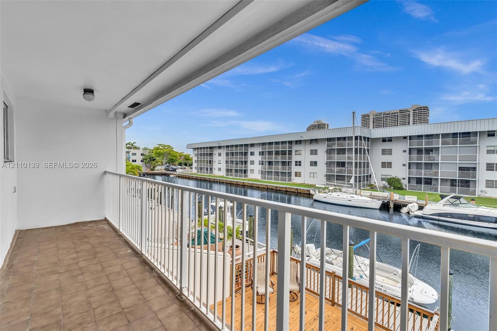 Covered balcony featuring tile flooring and metal railings, overlooking a canal with boat docking