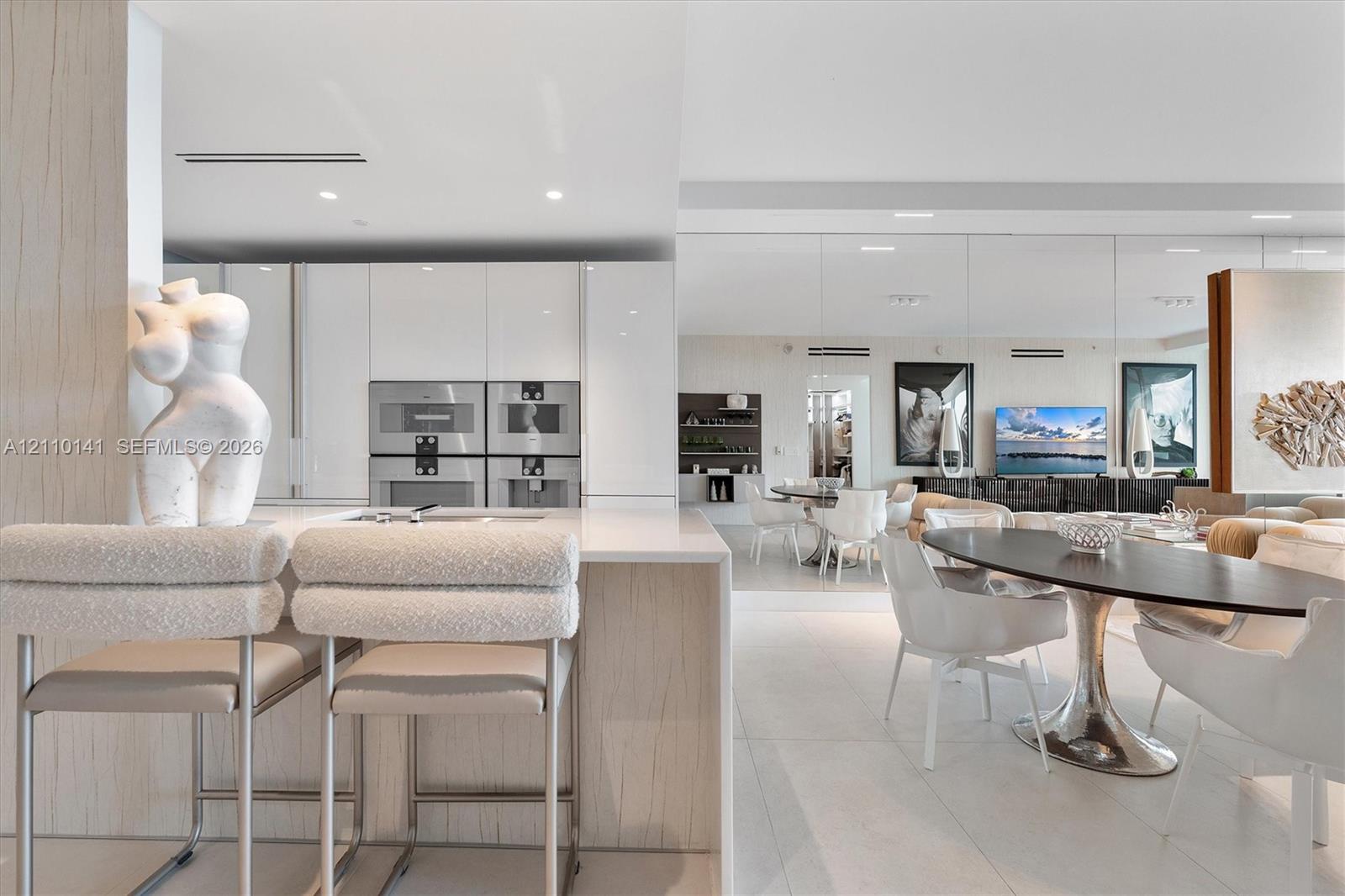 Modern kitchen featuring high-gloss cabinetry, stone-surface waterfall island, built-in dual stainless steel oven- microwave- integrated coffe sysstem for qulaity experience