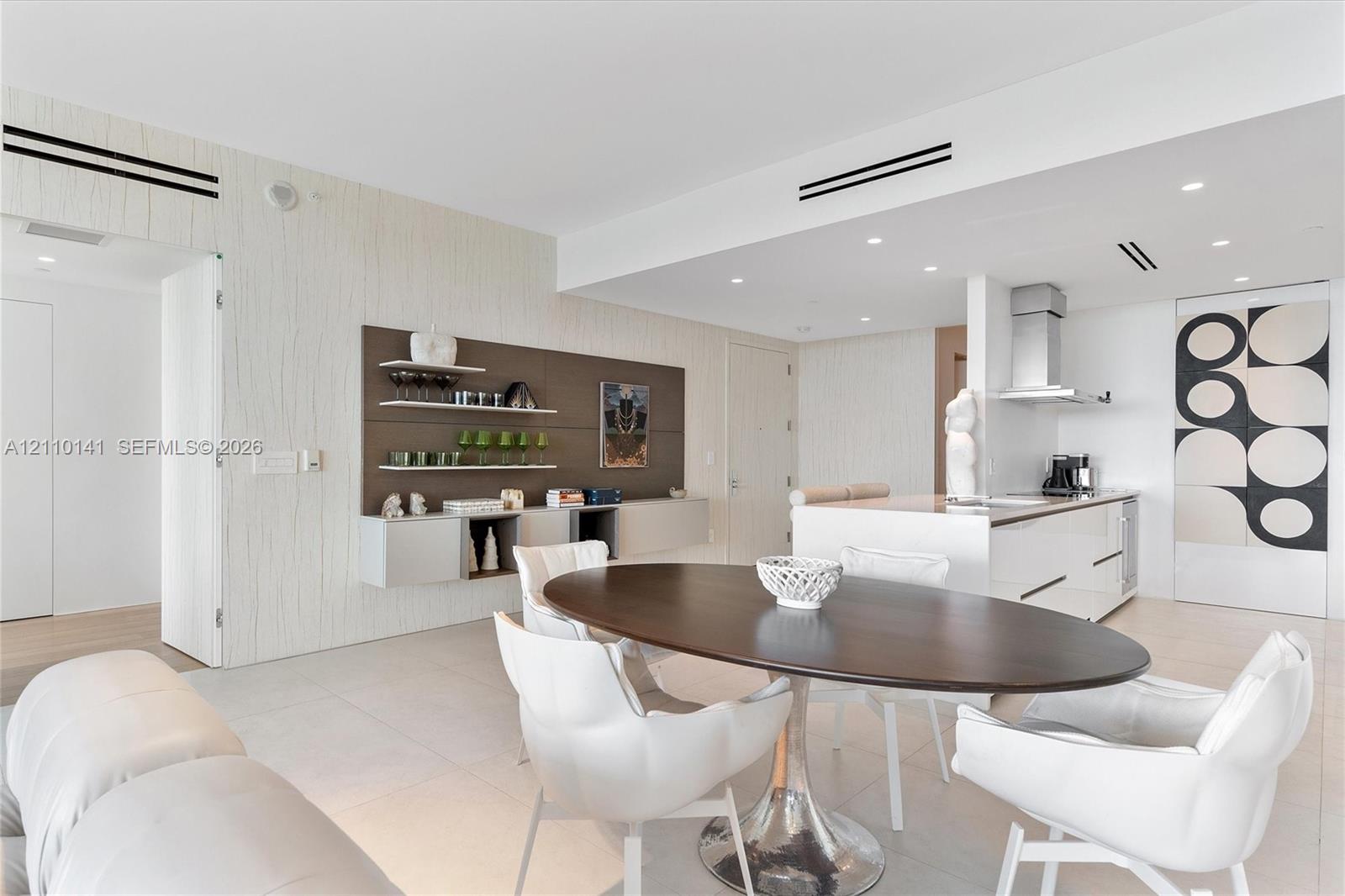 Open-concept interior, recessed ceiling lighting, a kitchen island with stone countertops, and built-in wall cabinetry
