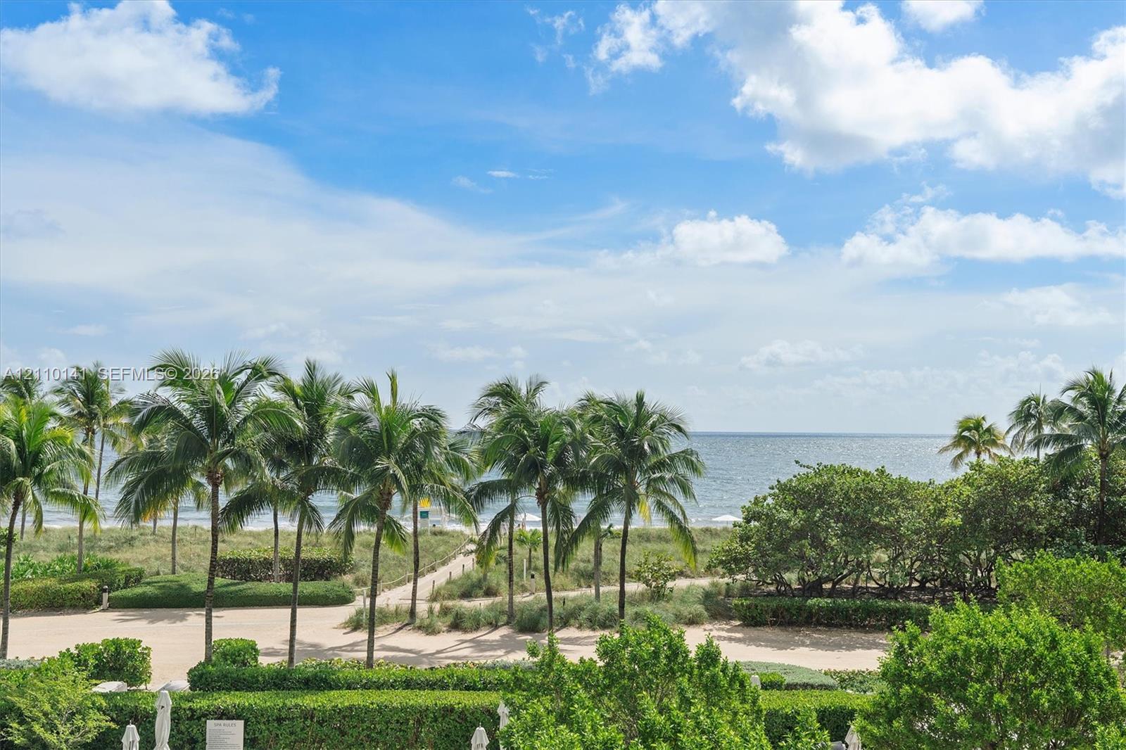 Coastal property featuring an expansive ocean horizon, mature palm trees, manicured hedges, and a private sand path leading to the beach. THE RESIDENCE IS A CORNER UNIT