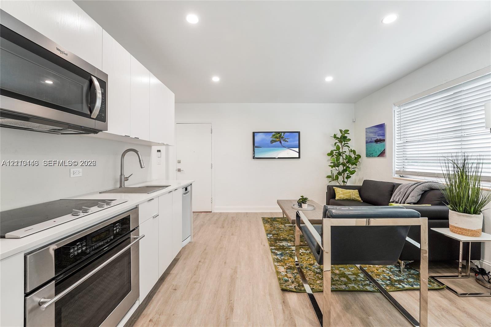 Kitchen featuring white flat-panel cabinetry, stainless steel appliances, recessed lighting, and wood-finish flooring