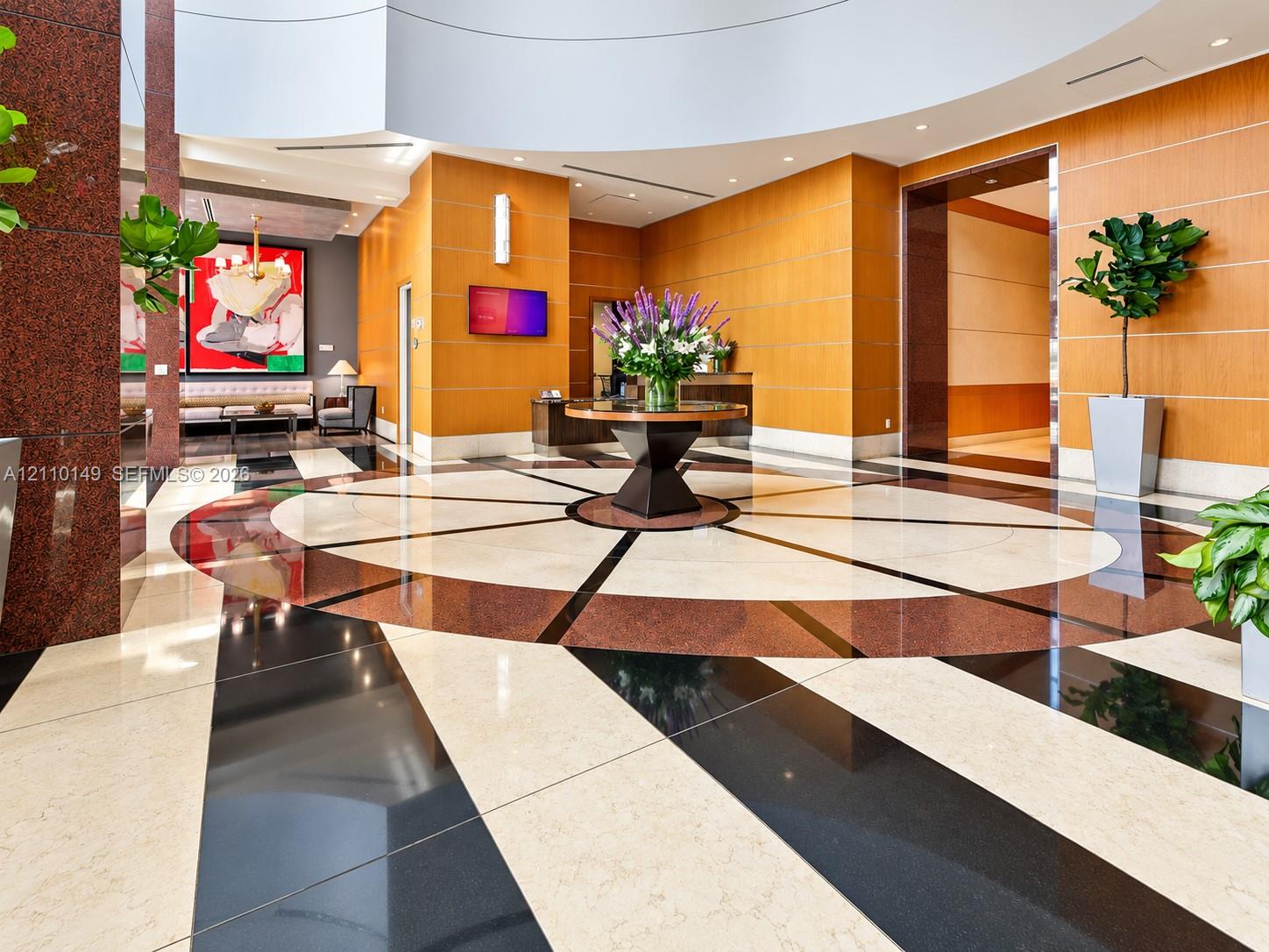 Grand lobby featuring a high, circular coffered ceiling, polished multi-toned stone flooring, and warm-toned paneled walls