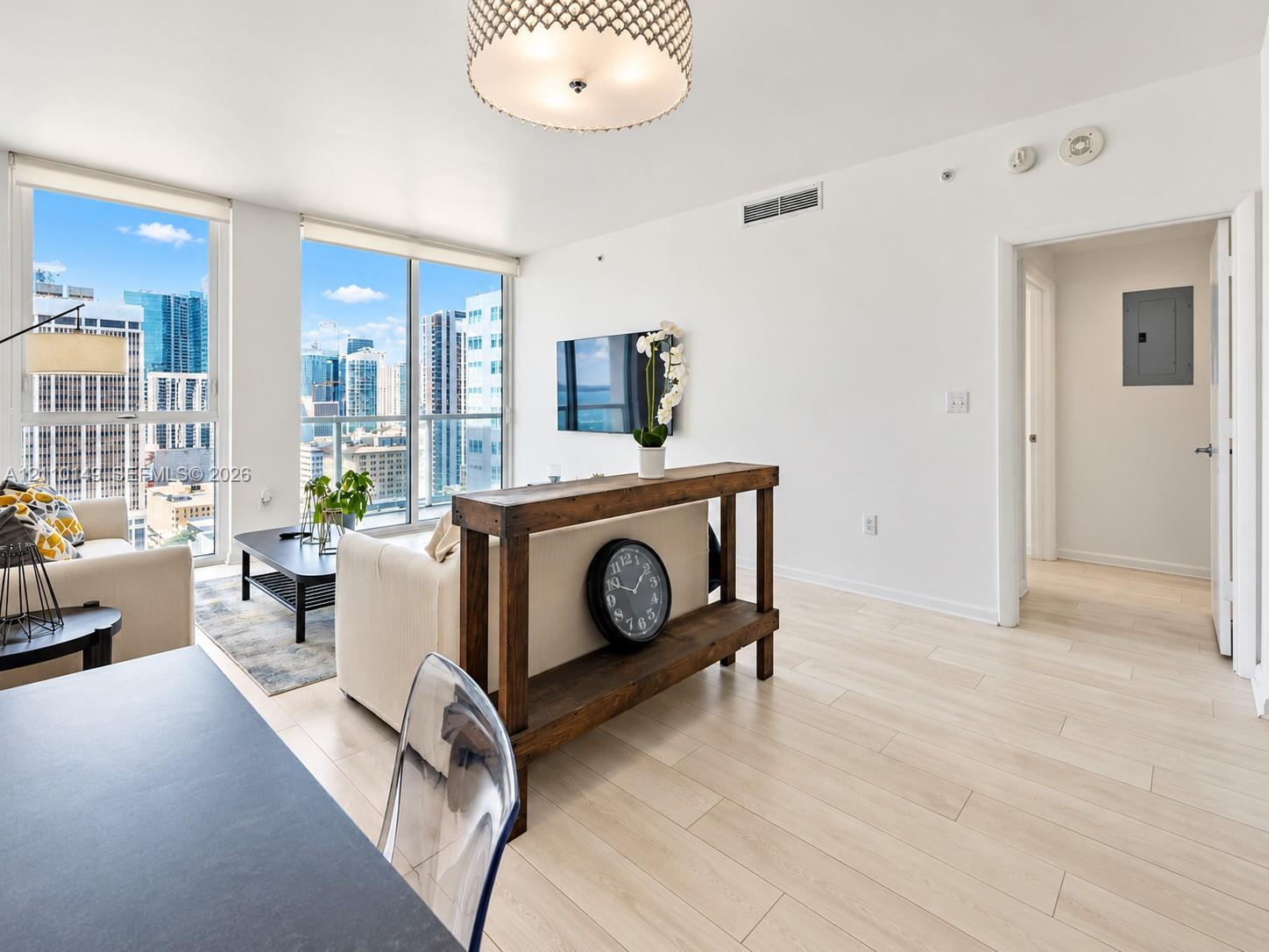 Floor-to-ceiling windows, wood-finish flooring, patterned drum pendant lighting, and urban skyline backdrop Floor-to-ceiling windows, wood-finish flooring, patterned drum pendant lighting, and urban skyline backdrop