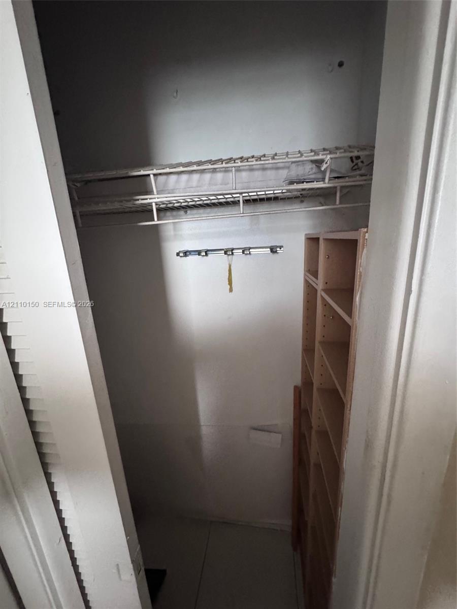 Storage area featuring wire shelving, a mounted hardware rack, and built-in vertical wooden shelving units