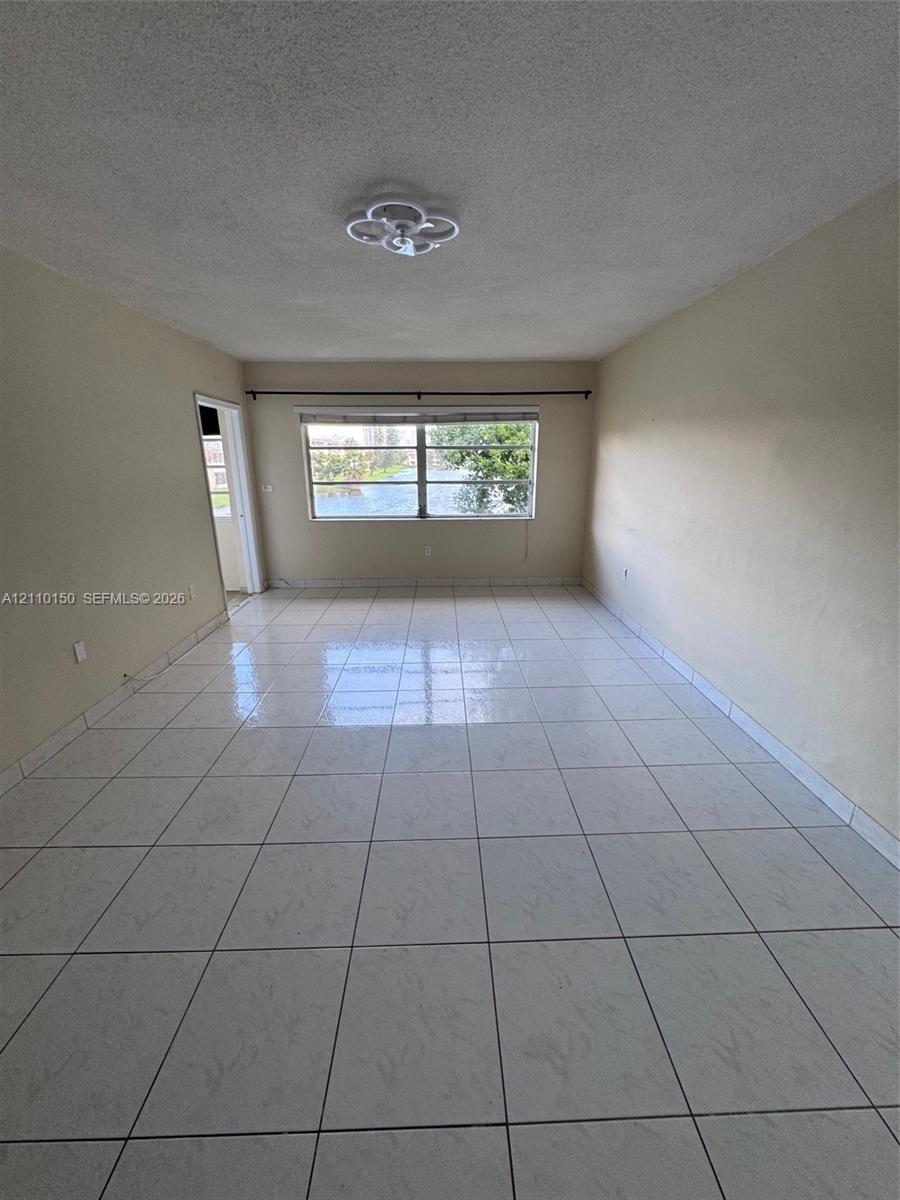 Neutral-toned interior space featuring light-colored square tile flooring and a ceiling-mounted flush light fixture