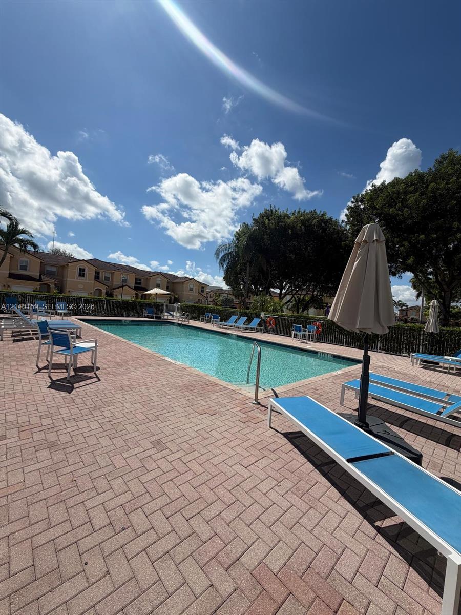 In-ground rectangular swimming pool with brick paver decking and metal perimeter fencing