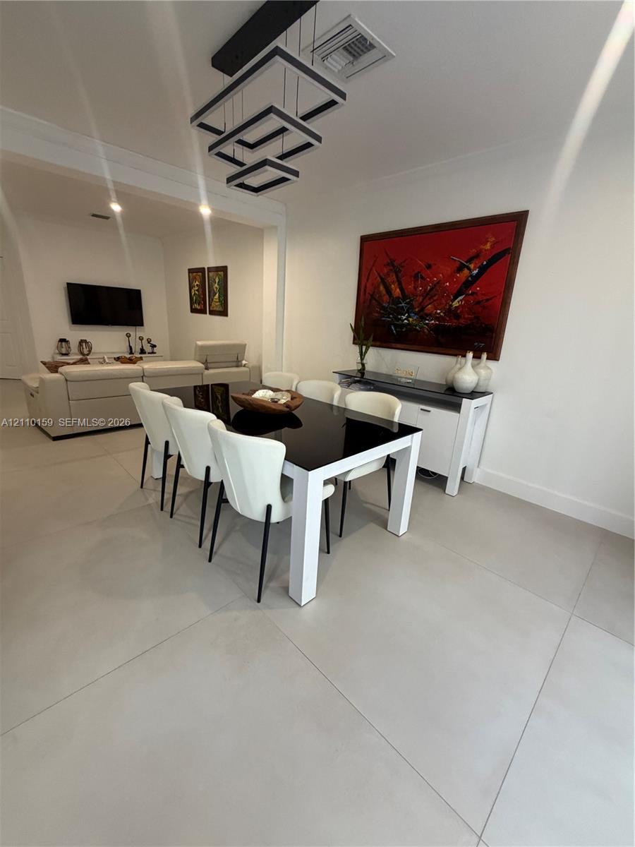 Large-format tile flooring, multi-tiered geometric pendant lighting, and crisp white wall finishes