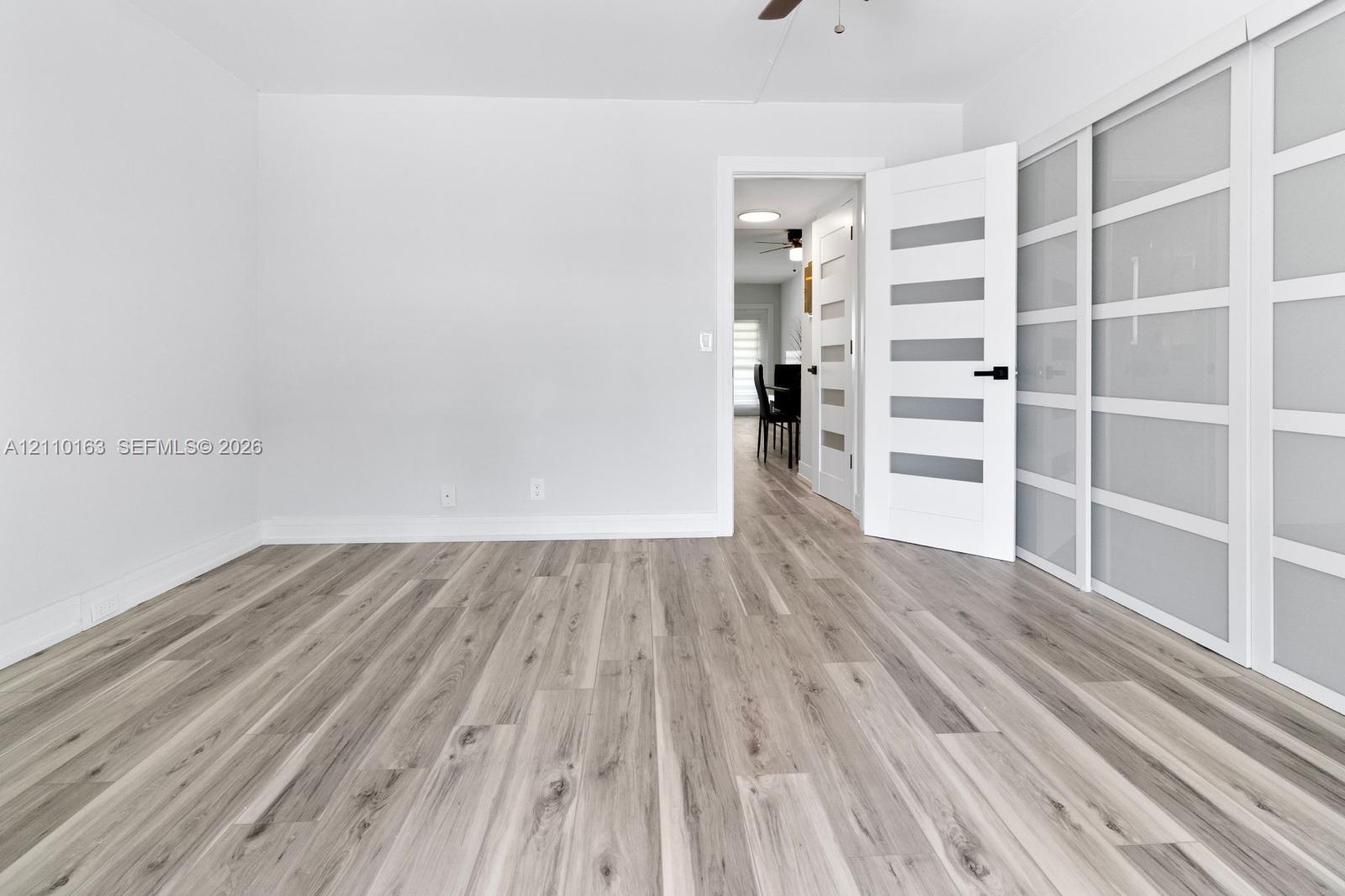 Wood-finish flooring, sliding glass-panel closet doors, and a six-panel door with frosted glass inserts featuring matte black hardware