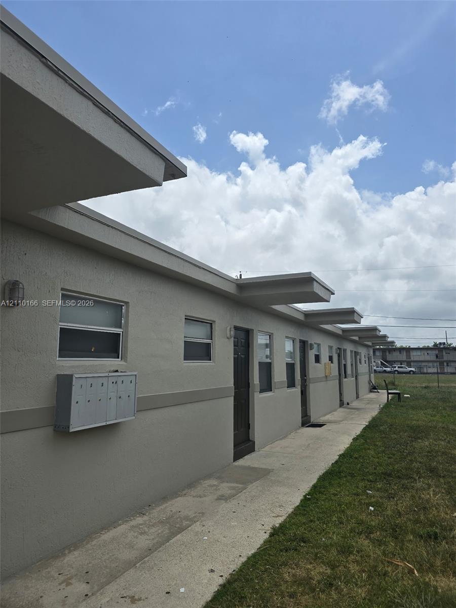 Exterior featuring a stucco facade, concrete walkway, and integrated wall-mounted mailboxes