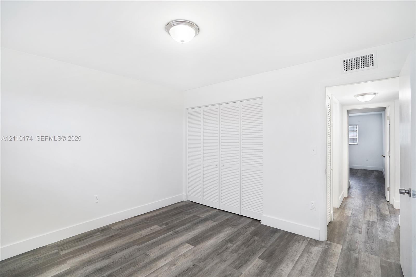 Wood-finish flooring, multi-panel louvered closet doors, and flush-mount ceiling lighting