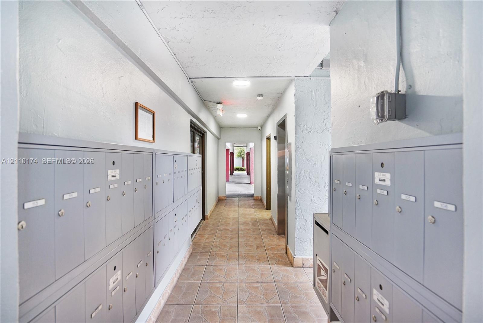 Interior corridor featuring wall-mounted metal mailboxes, flush-mount ceiling lighting, and tiled flooring