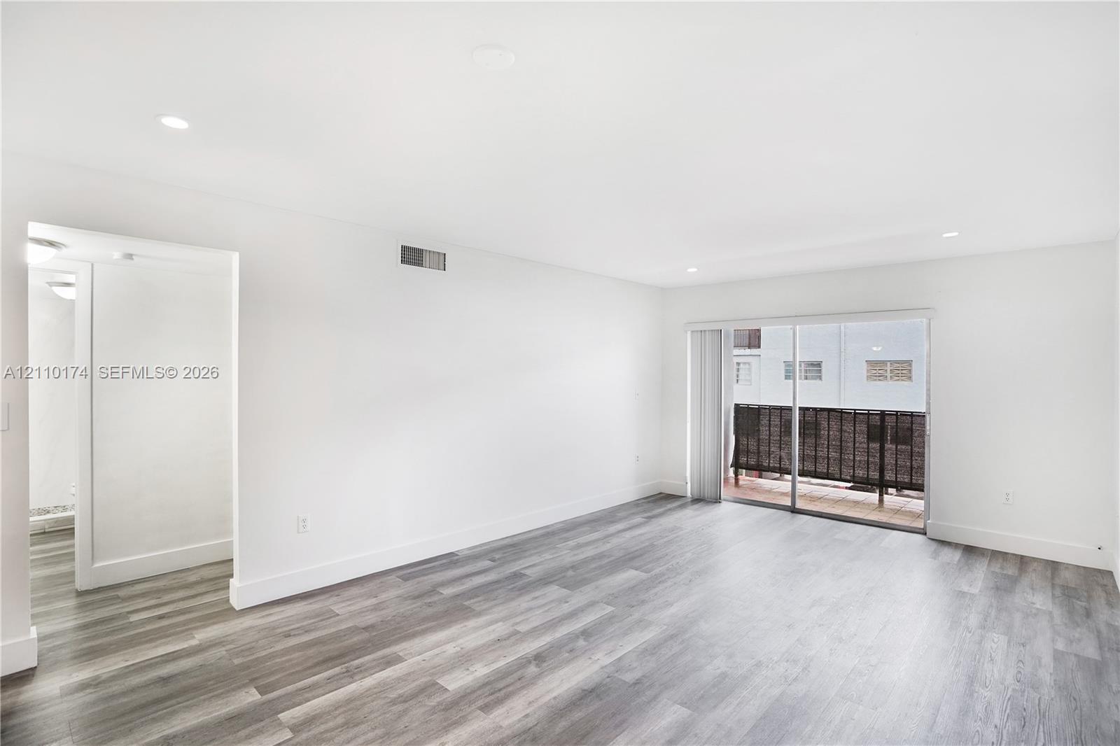 Interior space featuring wood-finish flooring, recessed lighting, and sliding glass doors with access to an exterior balcony Interior space featuring wood-finish flooring, recessed lighting, and sliding glass doors with access to an exterior balcony