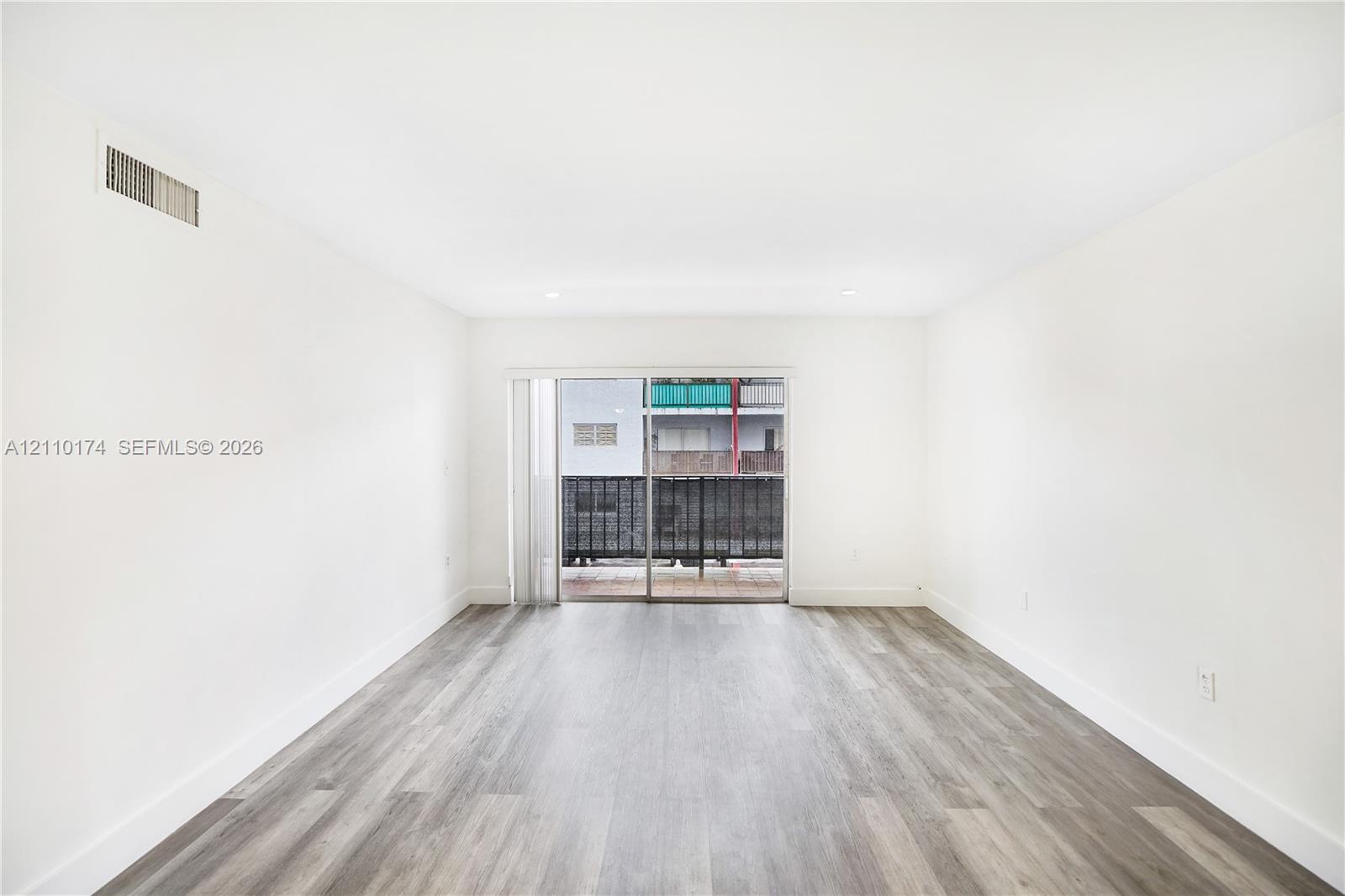 Interior space featuring wood-finish flooring, recessed lighting, and sliding glass doors with a metal railing