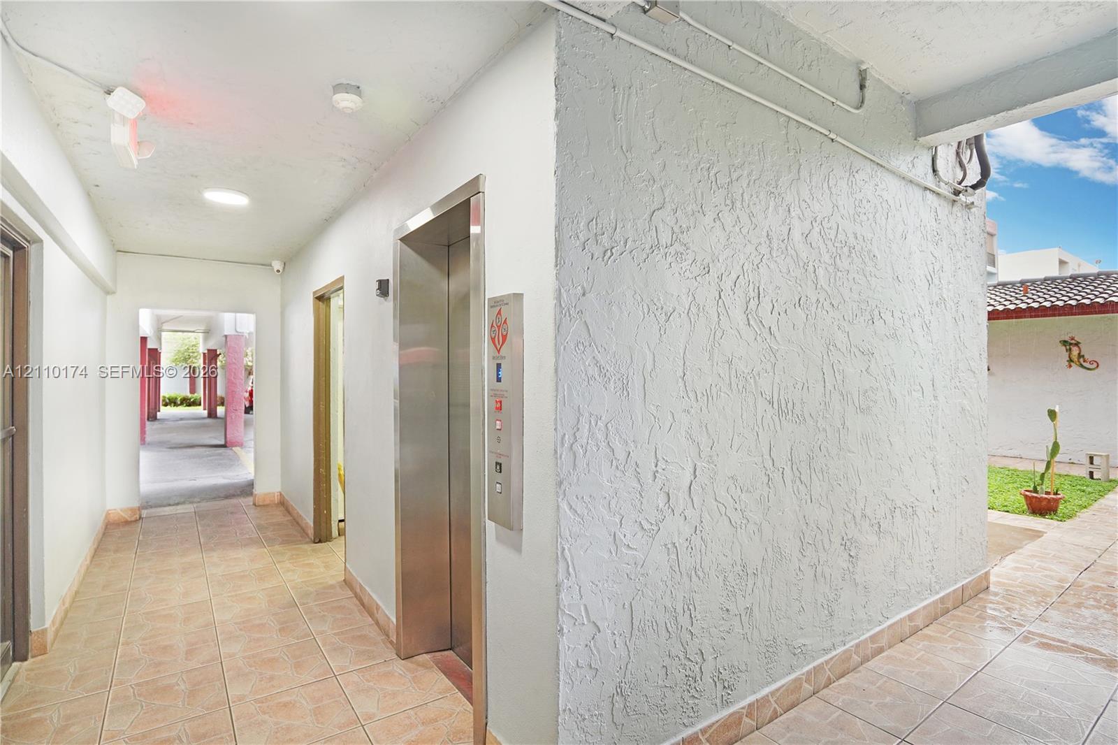 Elevator access area featuring textured wall finishes, tile flooring, and recessed ceiling lighting