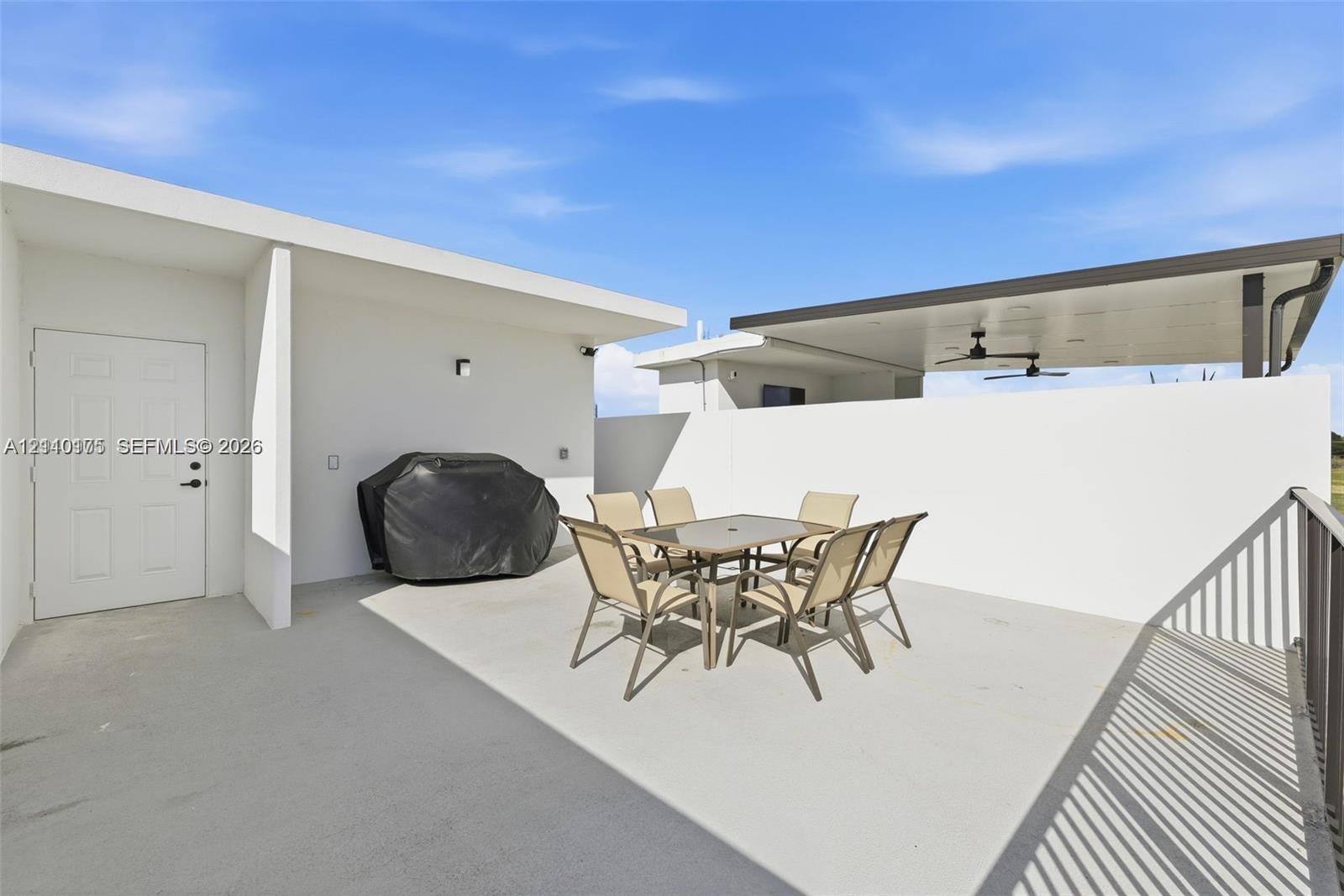 Outdoor terrace featuring concrete flooring, a covered patio area with dual ceiling fans, and a privacy wall