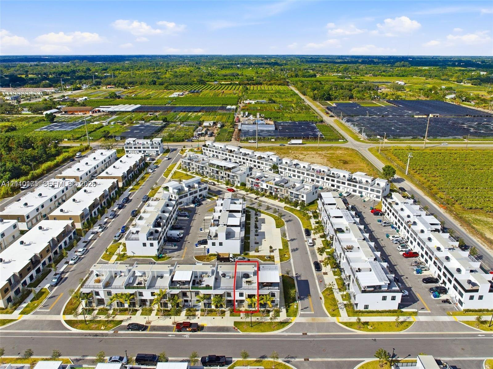 Aerial view featuring multi-level townhome architecture with flat rooflines, private rooftop terraces, and dedicated on-site parking within a residential community
