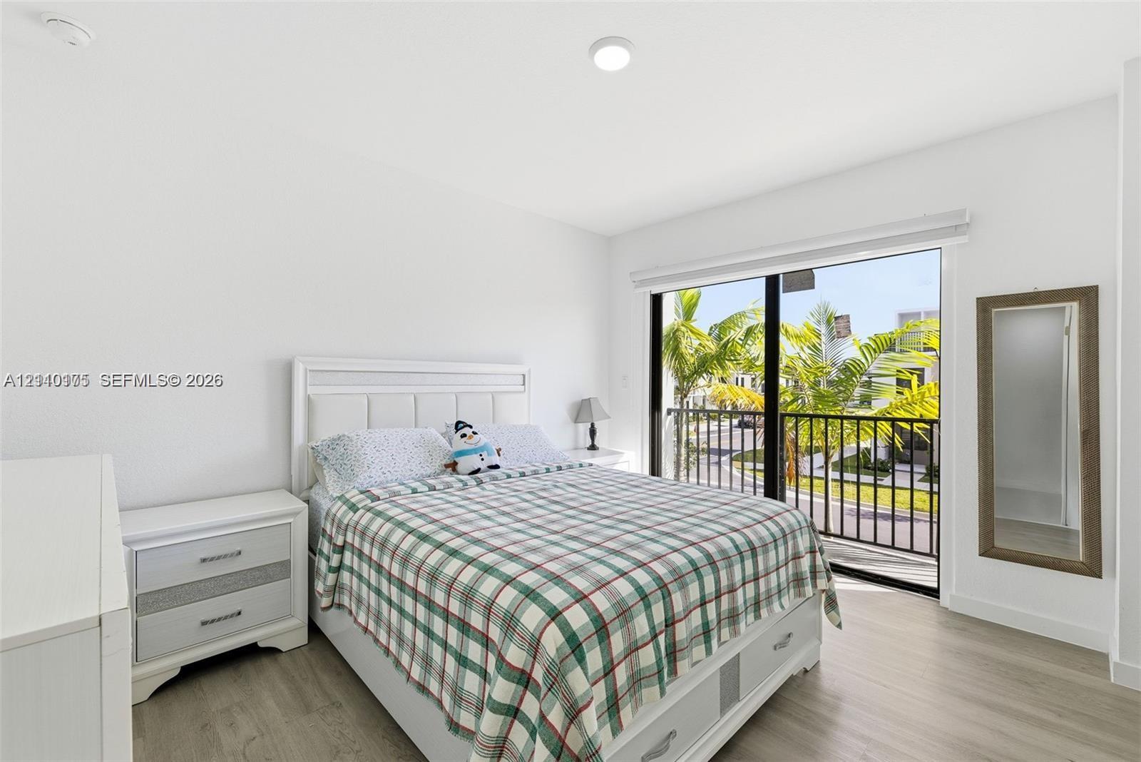 Bedroom featuring wood-finish flooring, recessed lighting, and a sliding glass door providing access to a balcony with metal railings