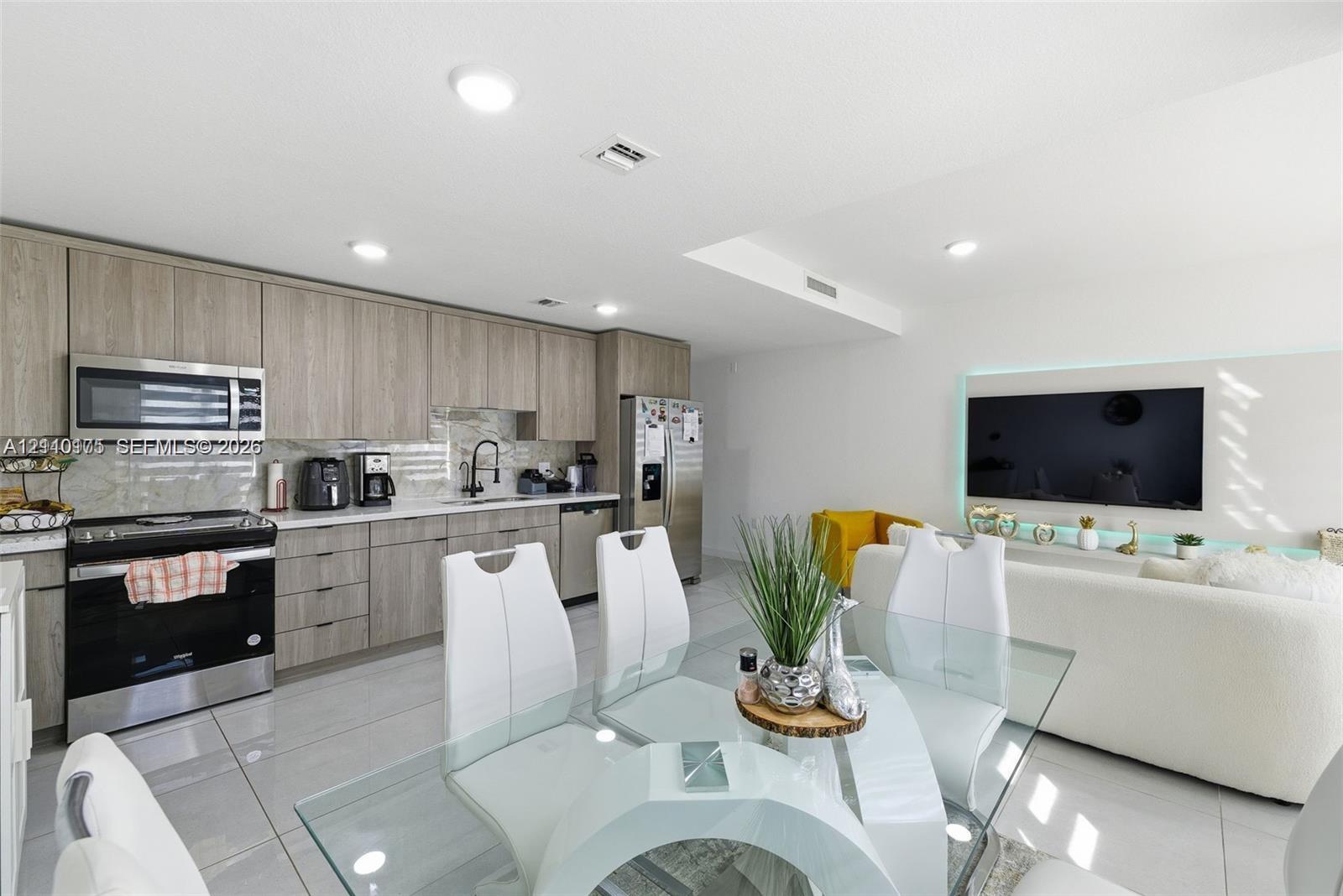 Kitchen featuring wood-finish flat-panel cabinetry, stone countertops, stainless steel appliances, recessed ceiling lighting, and porcelain tile flooring