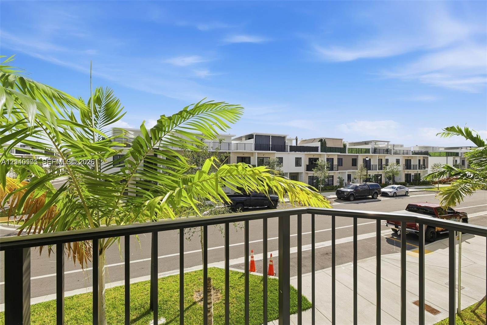 Exterior balcony featuring metal railings and palm foliage