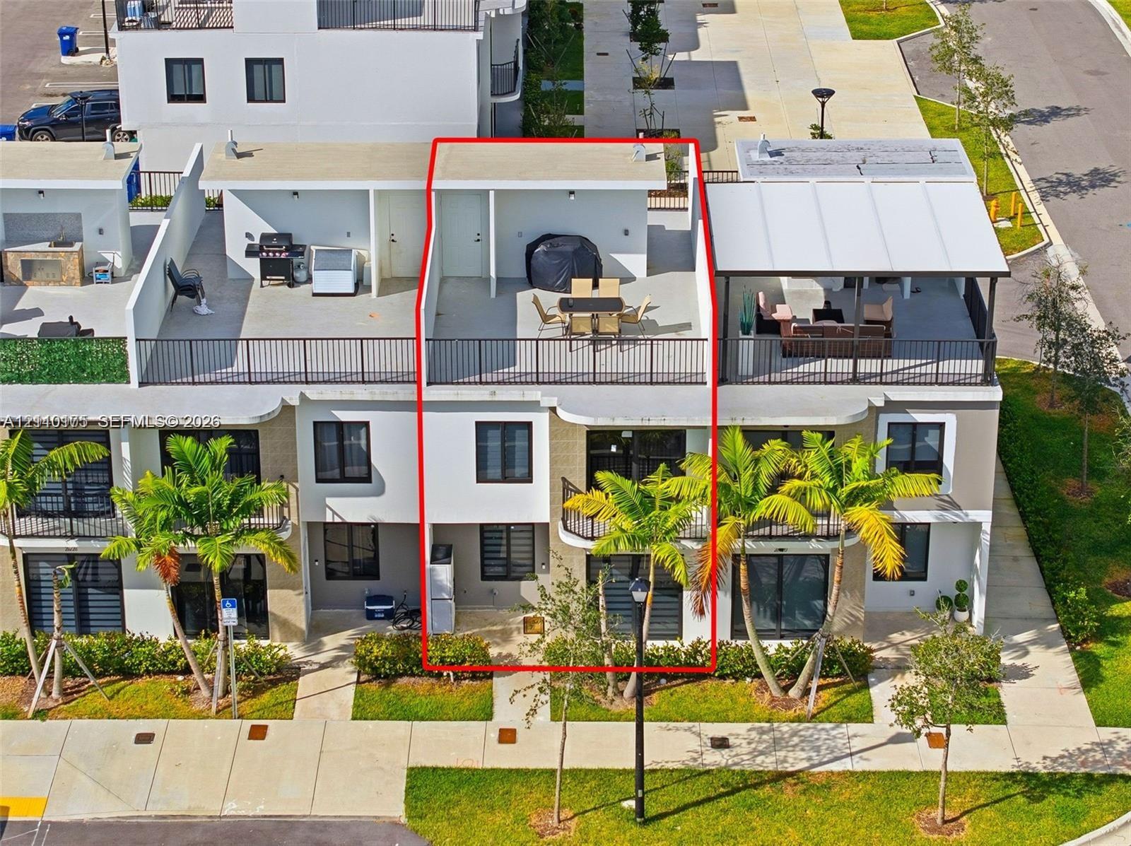 Multi-level townhome featuring a rooftop terrace with metal railings, glass sliding doors, dark-framed windows, and a paved ground-level entry area