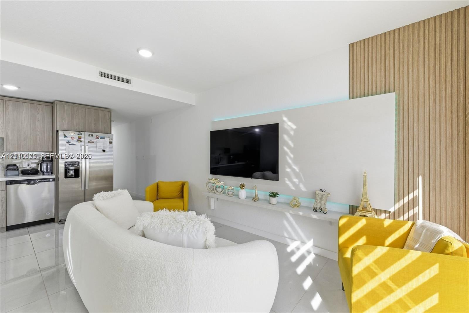 Modern interior featuring white tile flooring, custom slatted wood wall paneling, a minimalist built-in wall-mounted display shelf with integrated lighting, and stainless steel kitchen appliances