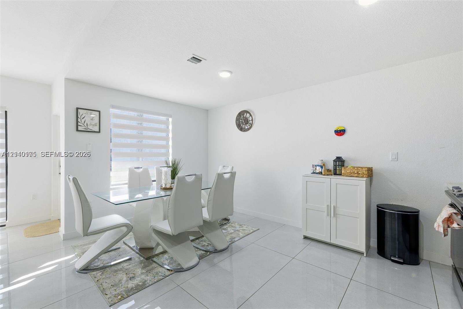Open-concept dining area featuring large-format tile flooring, recessed lighting, and dual-layered window shades
