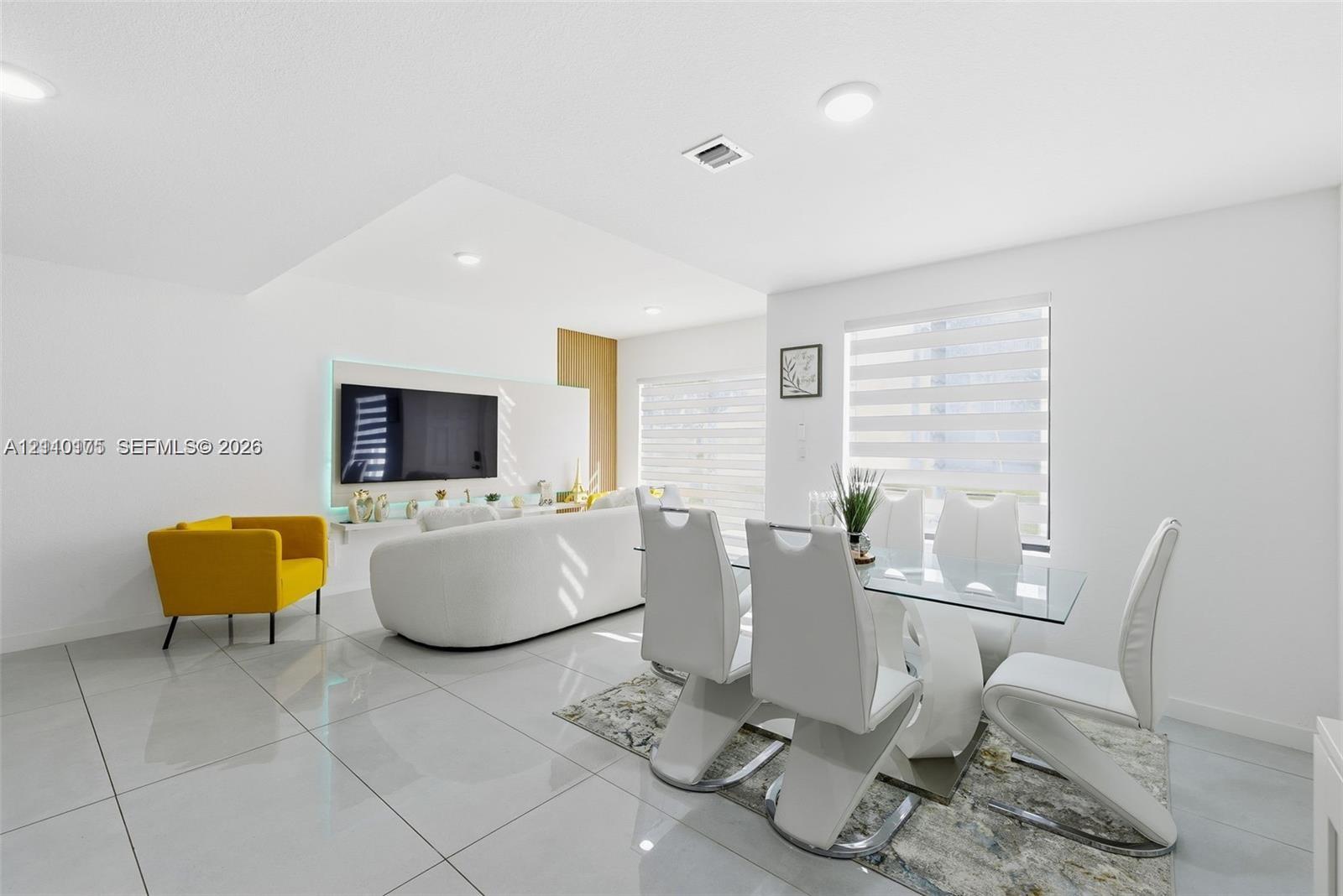 Large-format tile flooring, recessed ceiling lighting, and a custom media wall with integrated accent lighting