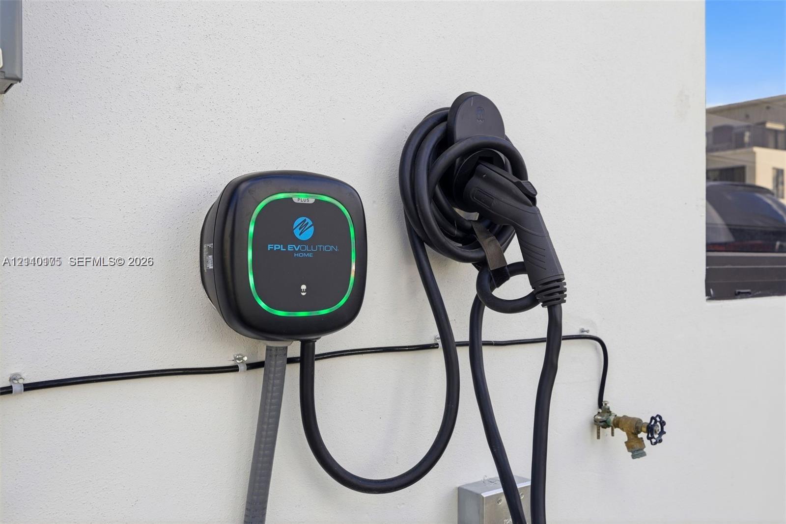 Wall-mounted electric vehicle charging station featuring a dedicated charging unit, coiled cord, and handle