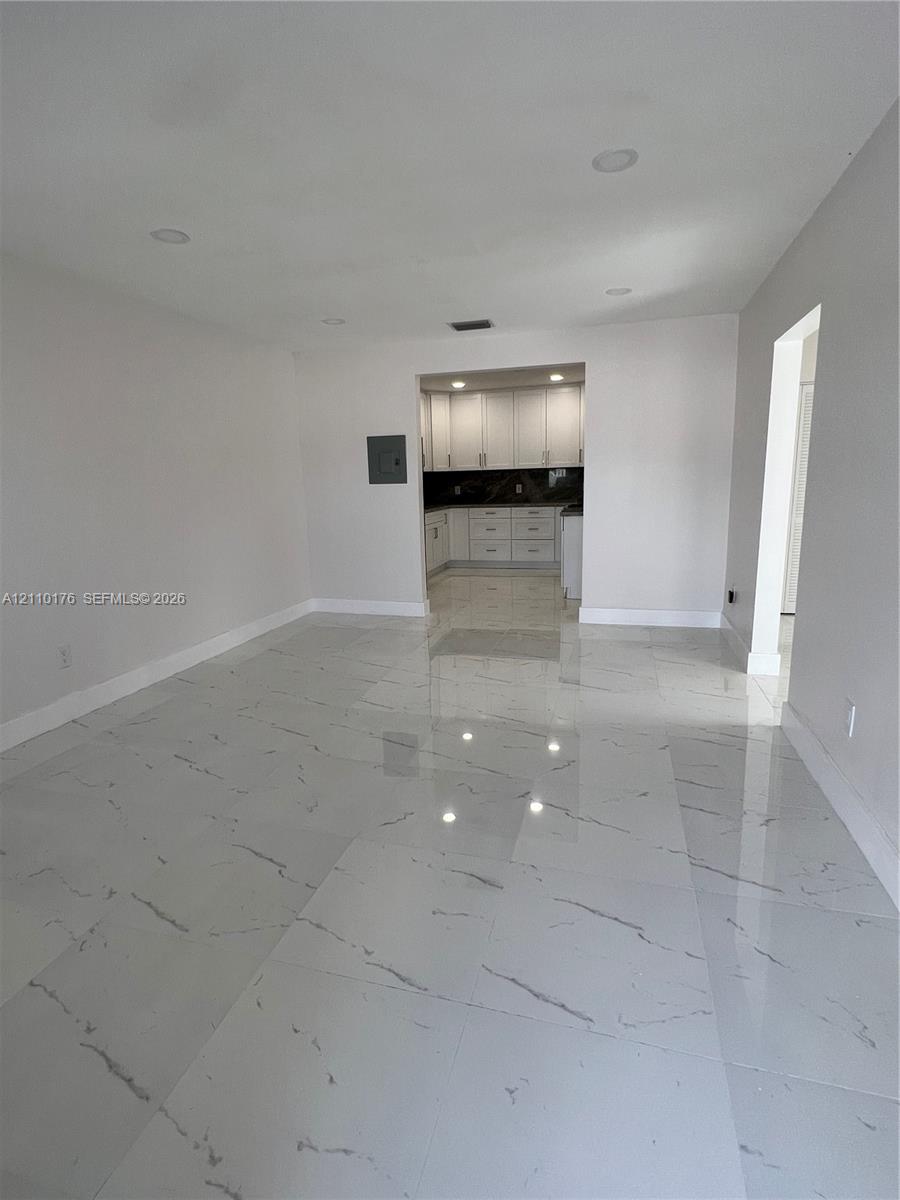 Large-format tile flooring with veining detail, recessed lighting, and white cabinetry