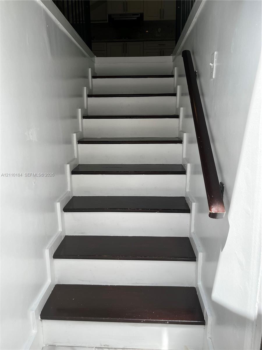 Staircase featuring dark-stained wood treads, white risers, and a dark-stained wood handrail