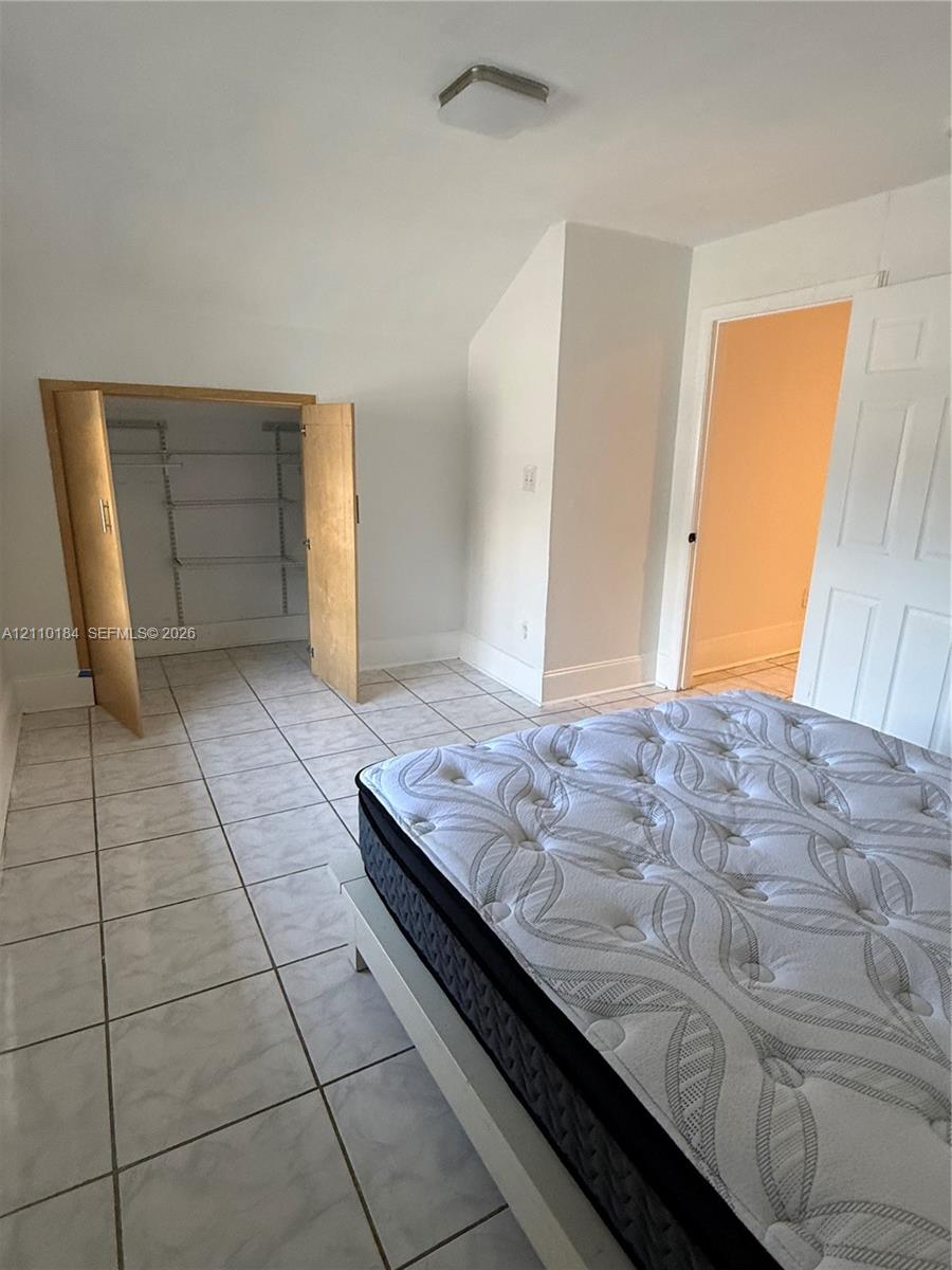 Ceramic tile flooring, built-in shelving unit, multi-panel interior door, and flush-mount ceiling light Ceramic tile flooring, built-in shelving unit, multi-panel interior door, and flush-mount ceiling light
