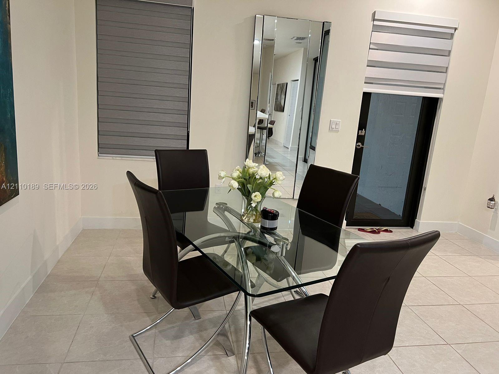Neutral-toned floor tiles, floor-to-ceiling wall mirror, and dual-layered window treatments