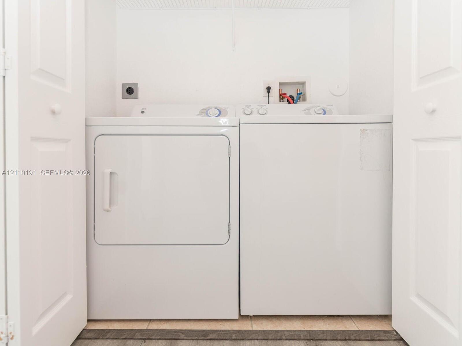 Laundry area featuring white paneled folding closet doors and tile flooring