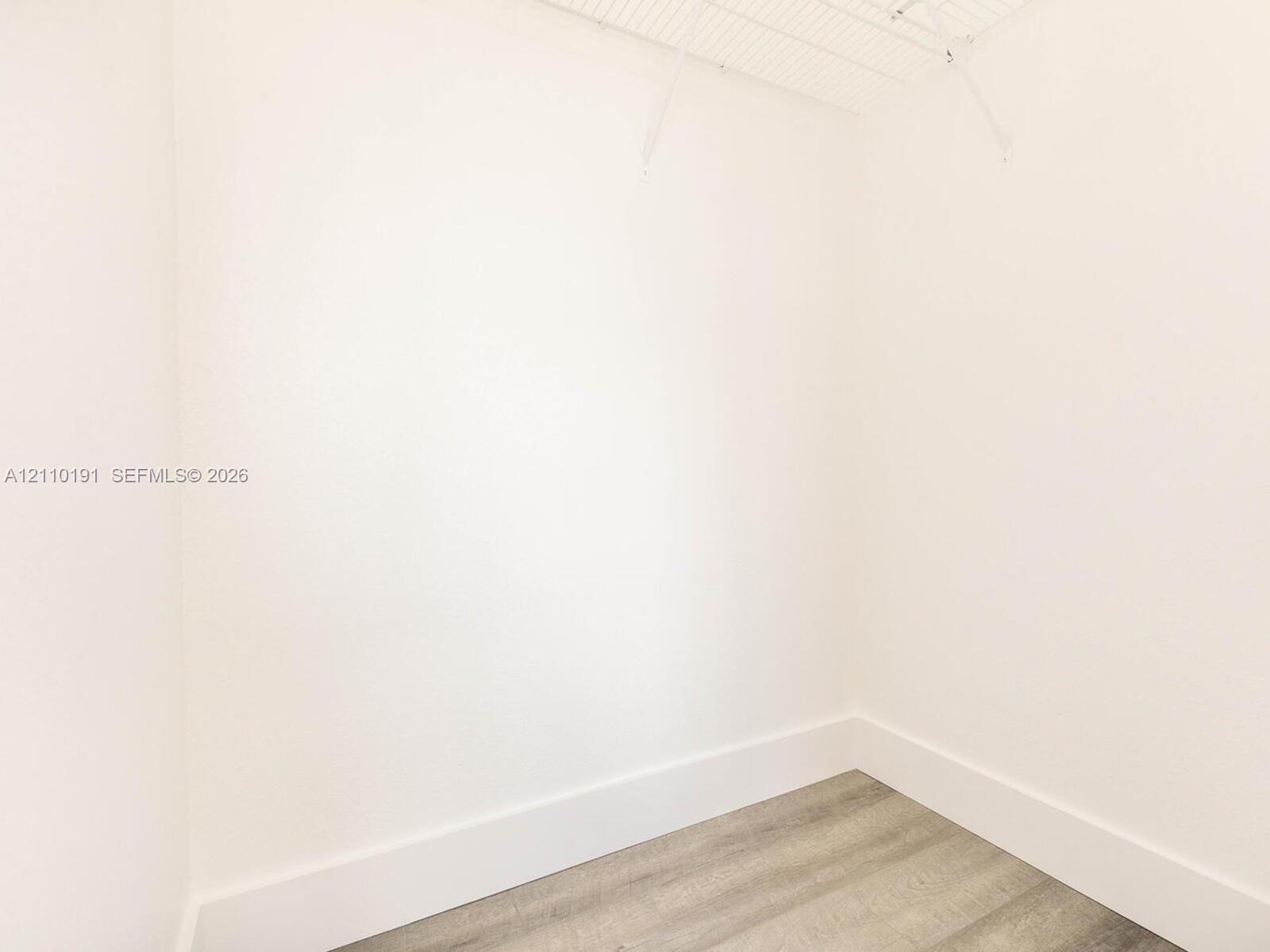 Walk-in closet featuring neutral walls, wood-finish flooring, and white wire shelving