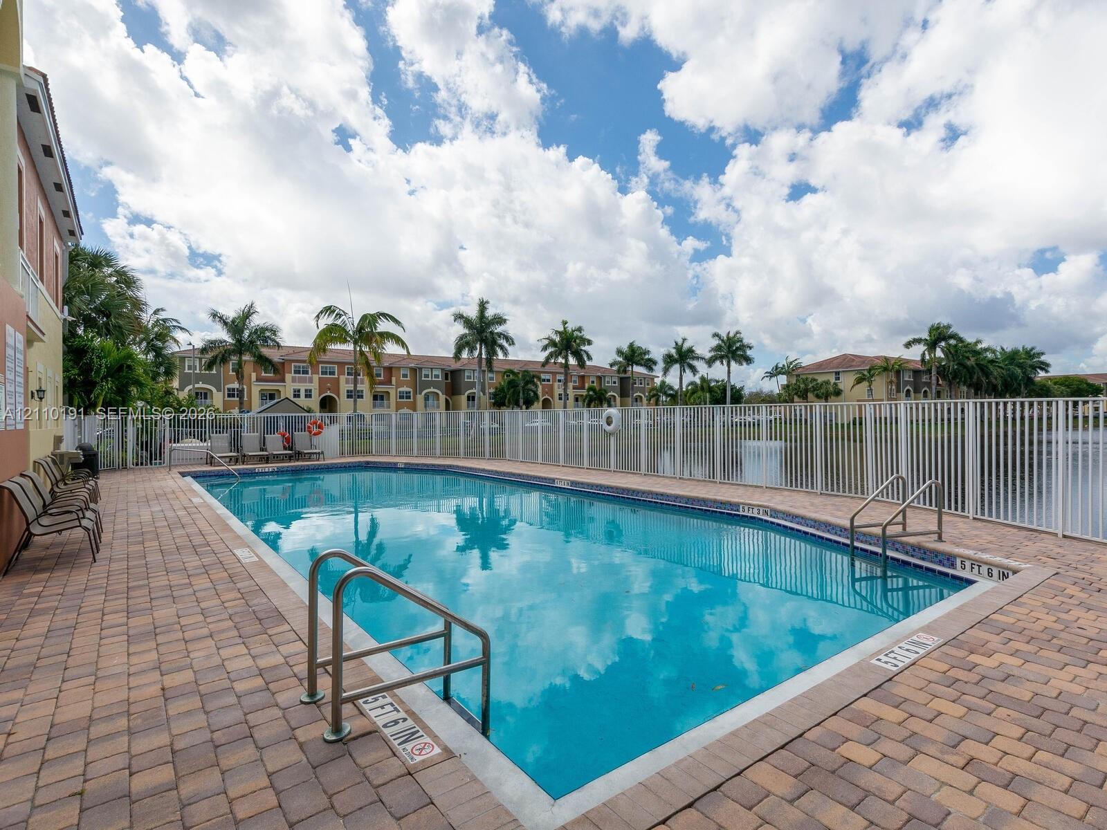 Outdoor swimming pool featuring a paver deck, metal fencing, and metal entry rails