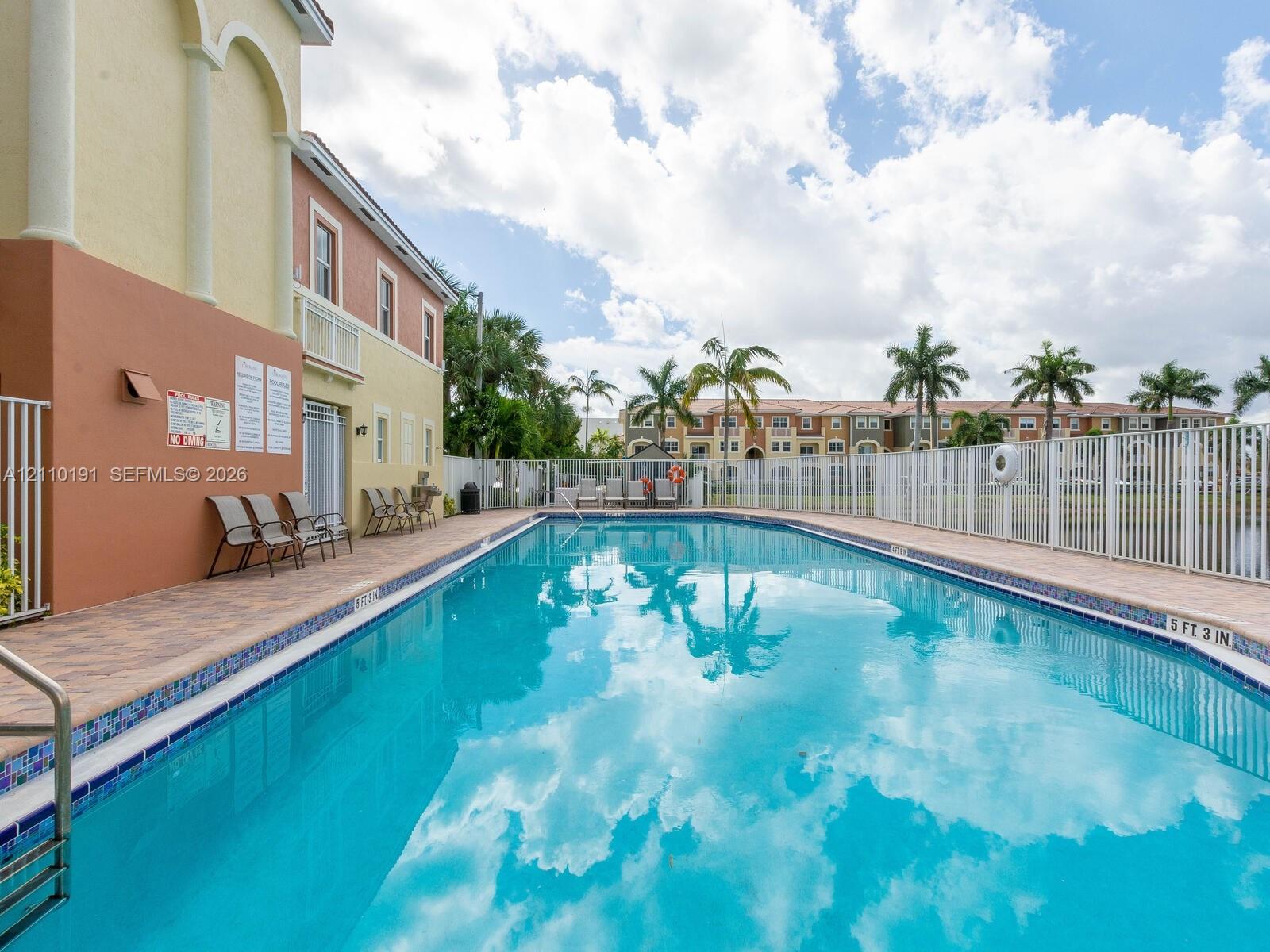 In-ground swimming pool featuring a tile border, metal perimeter fencing, and concrete paver deck