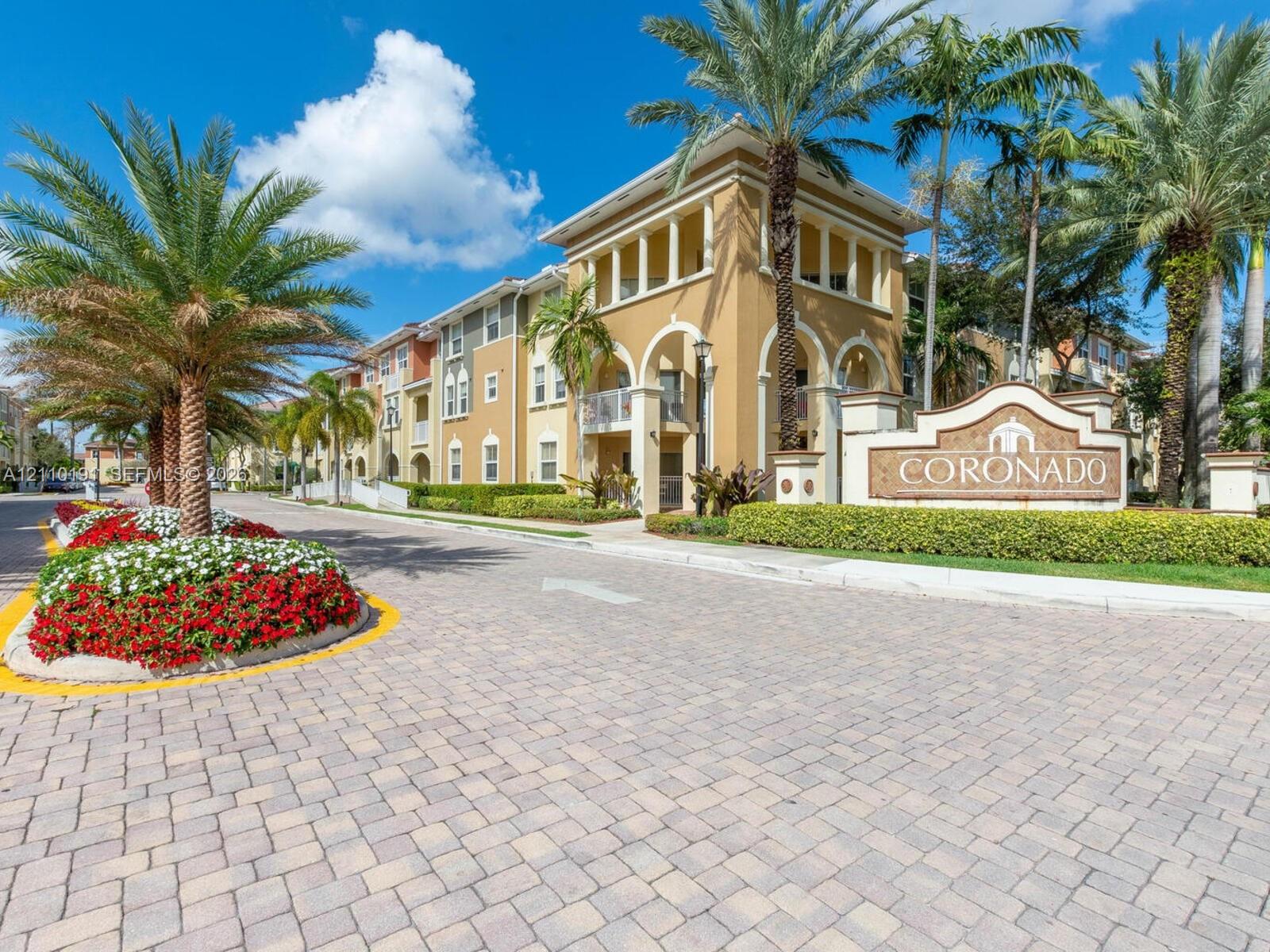 Stucco exterior featuring arched architectural detailing, paved stone driveway, and established tropical landscaping Stucco exterior featuring arched architectural detailing, paved stone driveway, and established tropical landscaping