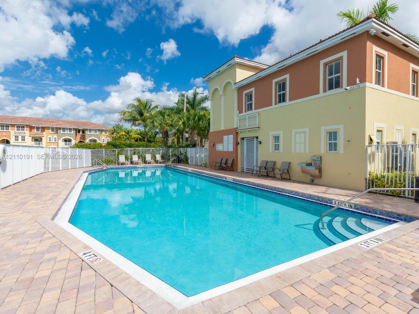 Swimming pool featuring integrated stair entry, light-toned masonry pavers, and perimeter metal fencing