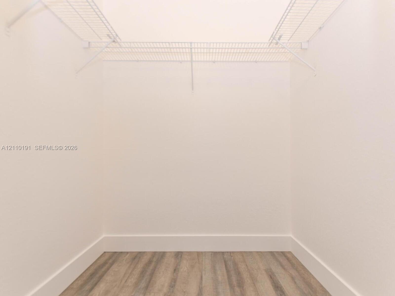 Walk-in closet featuring white wire shelving and wood-finish flooring
