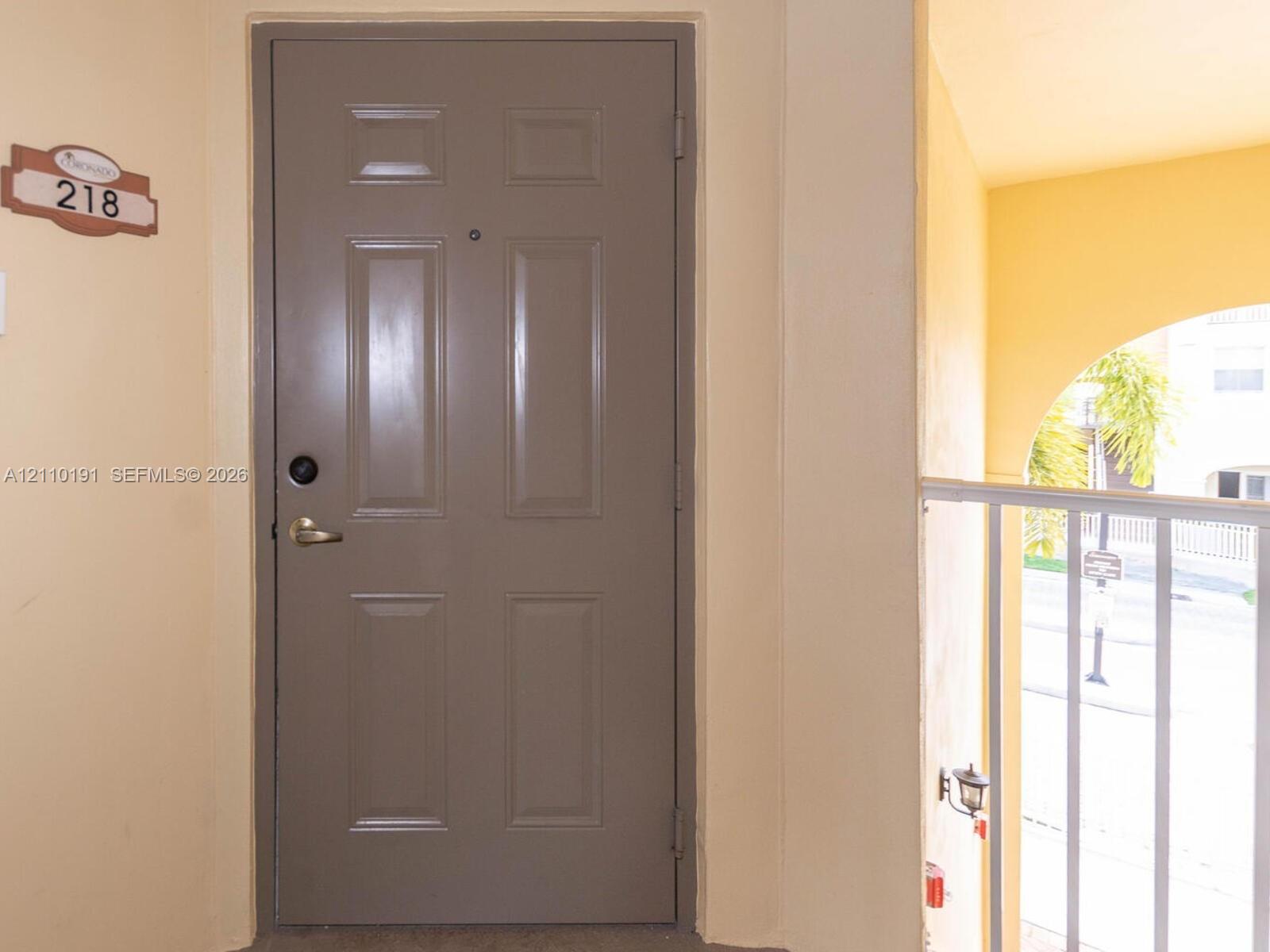 Solid-core, six-panel entry door featuring a matte finish lever handle, deadbolt lock, and an integrated door viewer