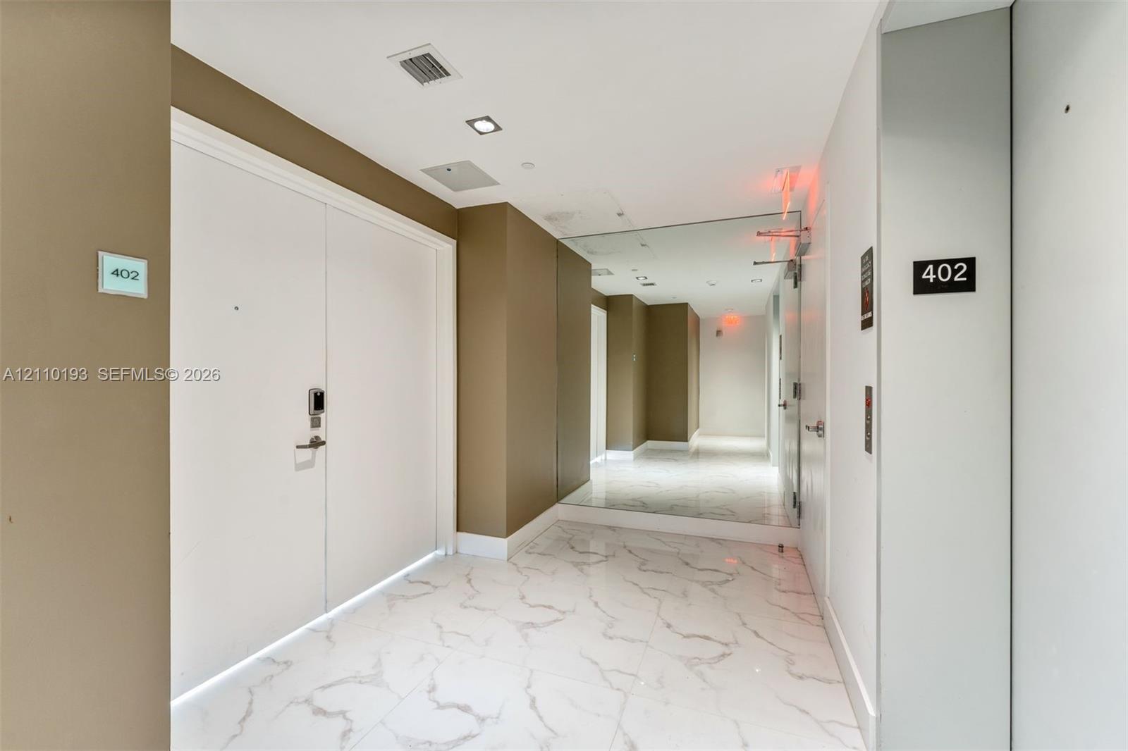 Entryway featuring polished stone-finish tile flooring, recessed ceiling lighting, and floor-to-ceiling mirror paneling