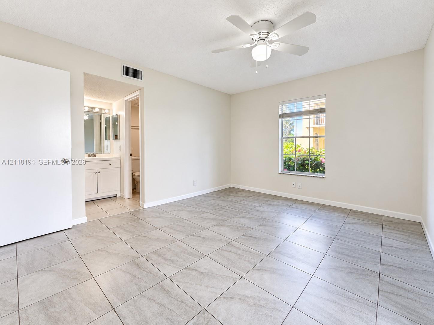 Room featuring large-format tile flooring, a multi-blade ceiling fan with an integrated light fixture, a single-hung window, and a white interior door