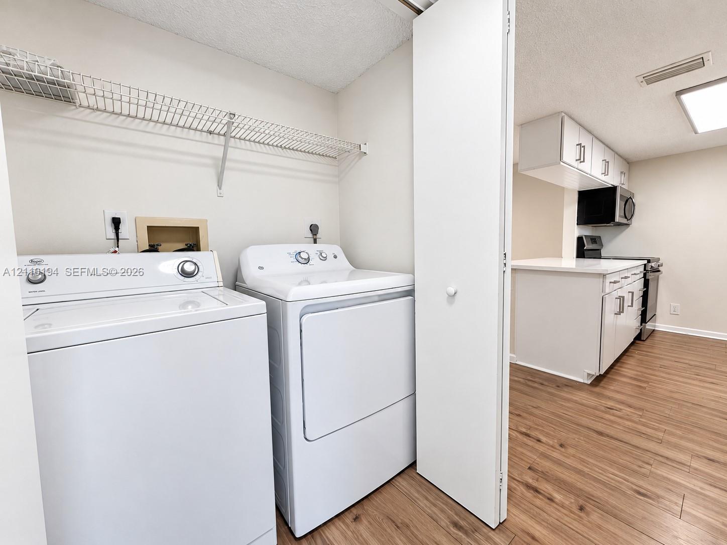 Laundry area featuring wire shelving and wood-finish flooring