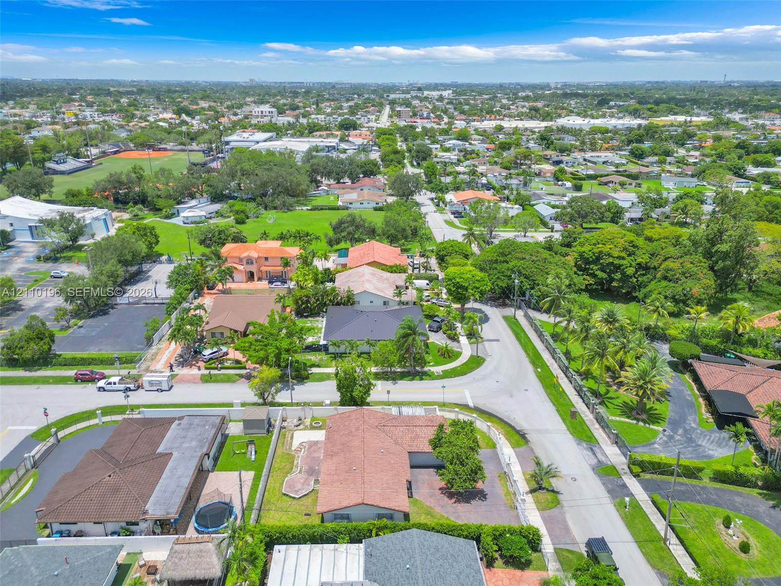 Aerial perspective of a suburban neighborhood featuring paved street infrastructure, mature landscaping, diverse residential roof styles, and abundant green space