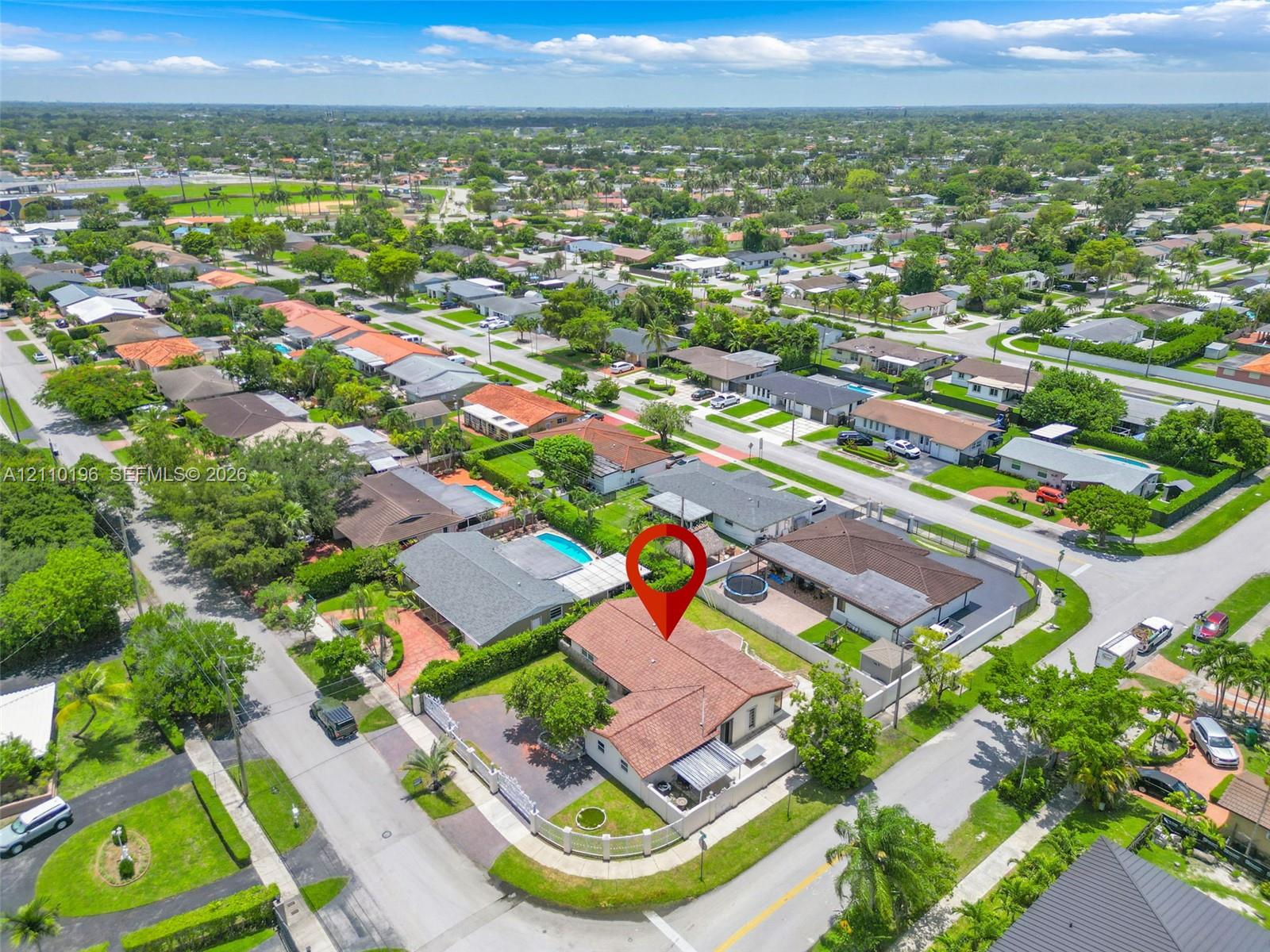 Aerial perspective of a residence featuring a clay tile roof, concrete perimeter wall, paved driveway, and mature landscaping
